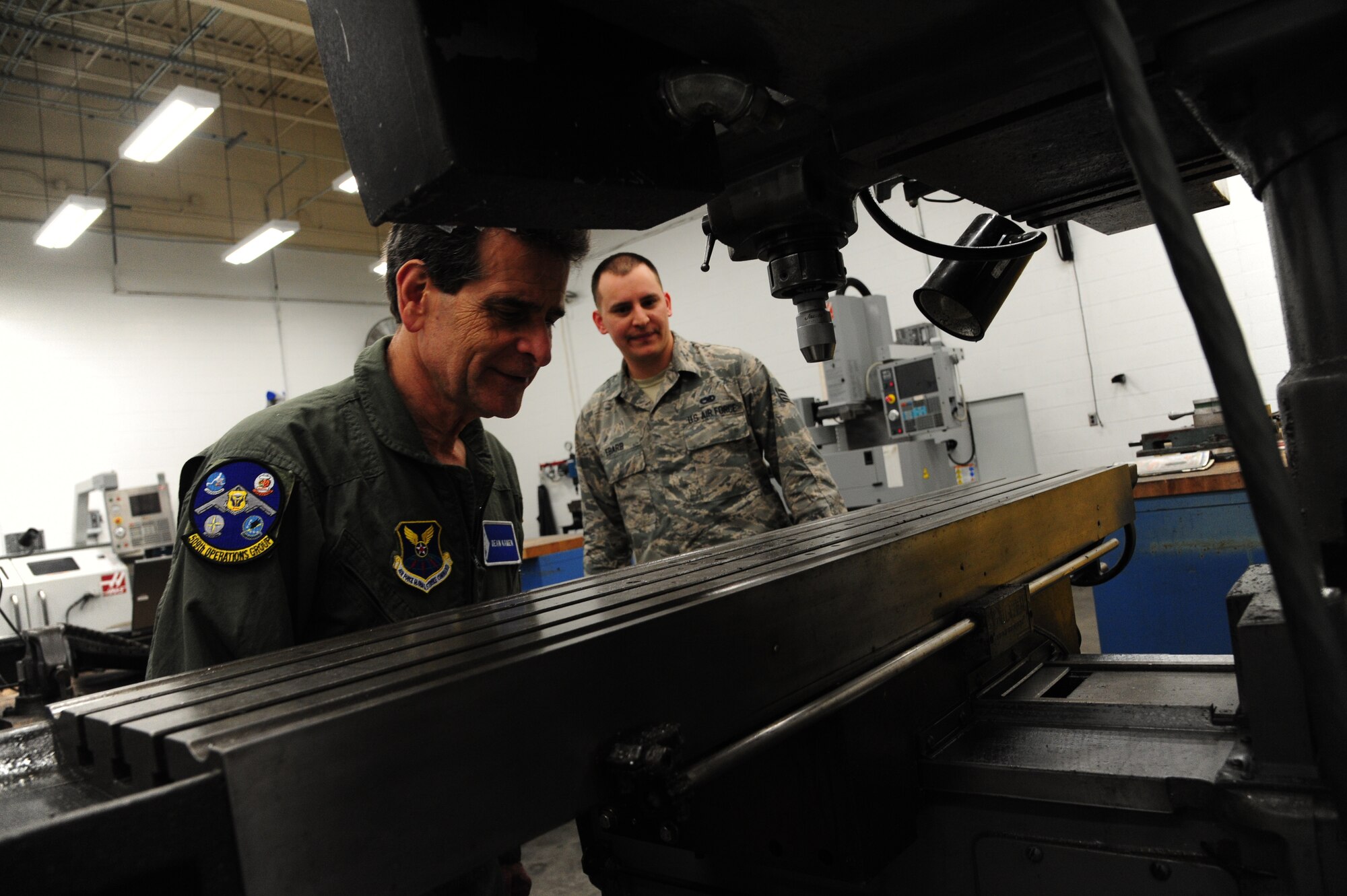 Dean Kamen, the FIRST Robotics founder, left, and U.S. Air Force Senior Airman Matthew Ebarb, a 509th Maintenance Squadron aircraft metals technician, view a milling machine at Whiteman Air Force Base, Mo., April 26, 2016. Kamen met Airmen and FIRST Robotics alumni during his visit and received an incentive flight in a B-2 Spirit. The U.S. Air Force and FIRST Robotics share an interest in developing youth into future leaders through exposure to education in science, technology, engineering and mathematics. (U.S. Air Force photo by Airman 1st Class Keenan Berry)