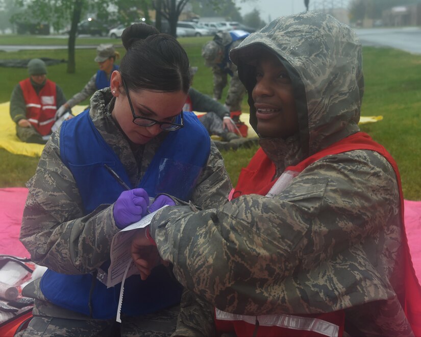 Staff Sgt. April Martinez, 779th Medical Group NCO in-charge of the Pentagon flight medicine annex, left, writes medical information on the simulated injured Airman during a Chemical, Biological, Radiological, Nuclear and Explosives training exercise at Joint Base Andrews, Md., April 28, 2016. The scenario simulated a disgruntled Airman that released ammonia on base to cause mass casualties in the contamination area. (U.S. Air Force photo by Senior Airman Dylan Nuckolls/Released)