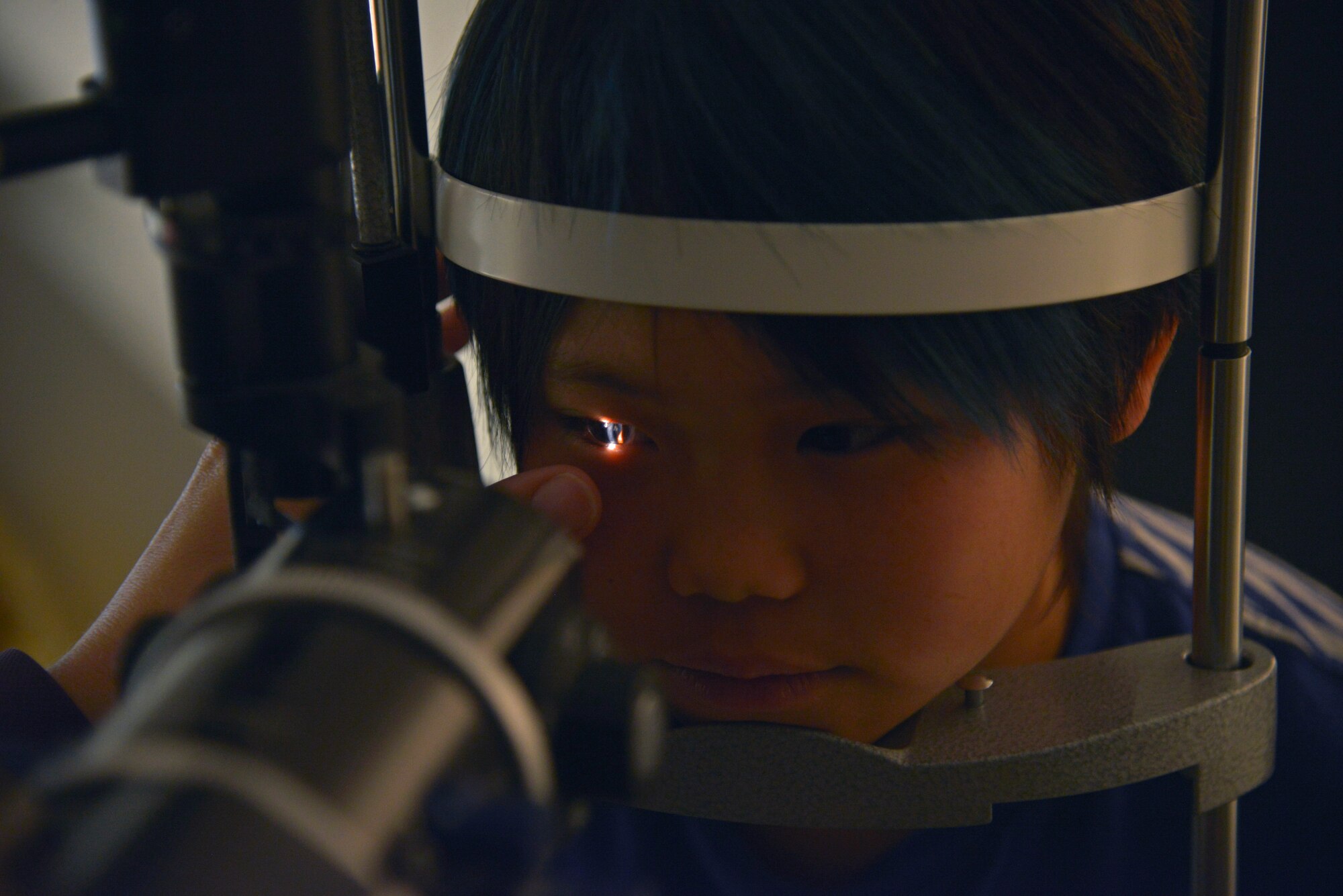Michelle Durham, American Red Cross optometrist, looks at the front part of an eye of Seina Karr, 12, daughter of Tech Sgt. Ryan Karr, 374th Civil Engineer Squadron, during a routine eye exam at Yokota Air Base, Japan, April 26, 2016. The clinic takes care of service members, Department of Defense employees and their dependent’s visual needs. (U.S. Air Force photo by Senior Airman David Owsianka/Released)