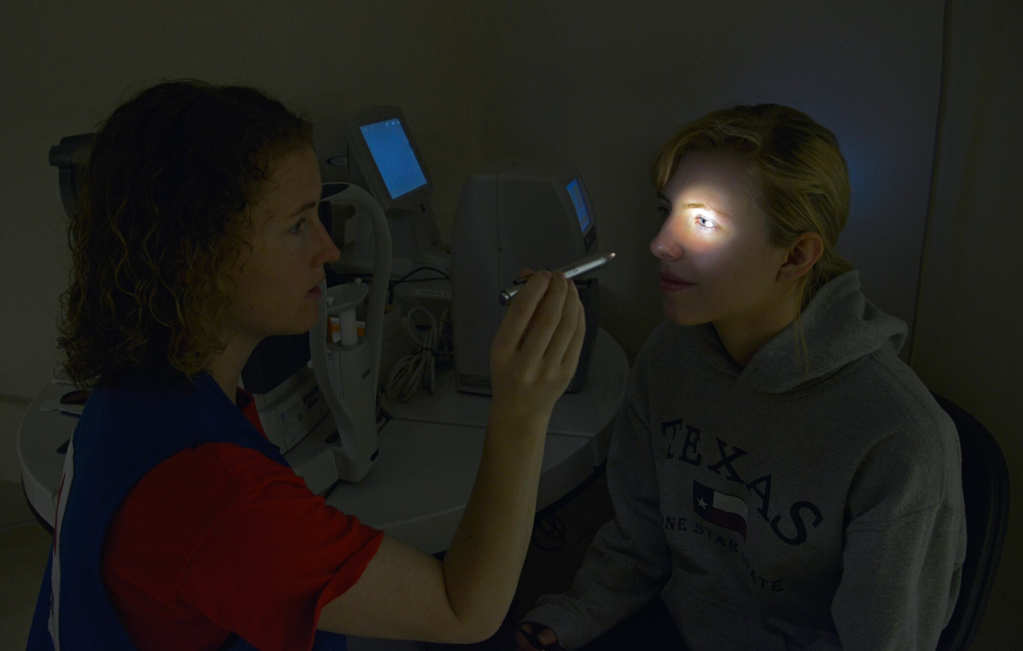 Kristen Judd, American Red Cross medical technician volunteer, checks the pupils of Teresa Talley, 19, daughter of Master Sgt. Thomas Talley, 374th Logistics Readiness Squadron fuels mobility support section chief, to make sure they are equal in size at Yokota Air Base, Japan, April 26, 2016. The clinic takes care of approximately 5,000 personnel annually and provides diagnosis and treatment for vision and ocular disorders. (U.S. Air Force photo by Senior Airman David Owsianka/Released)