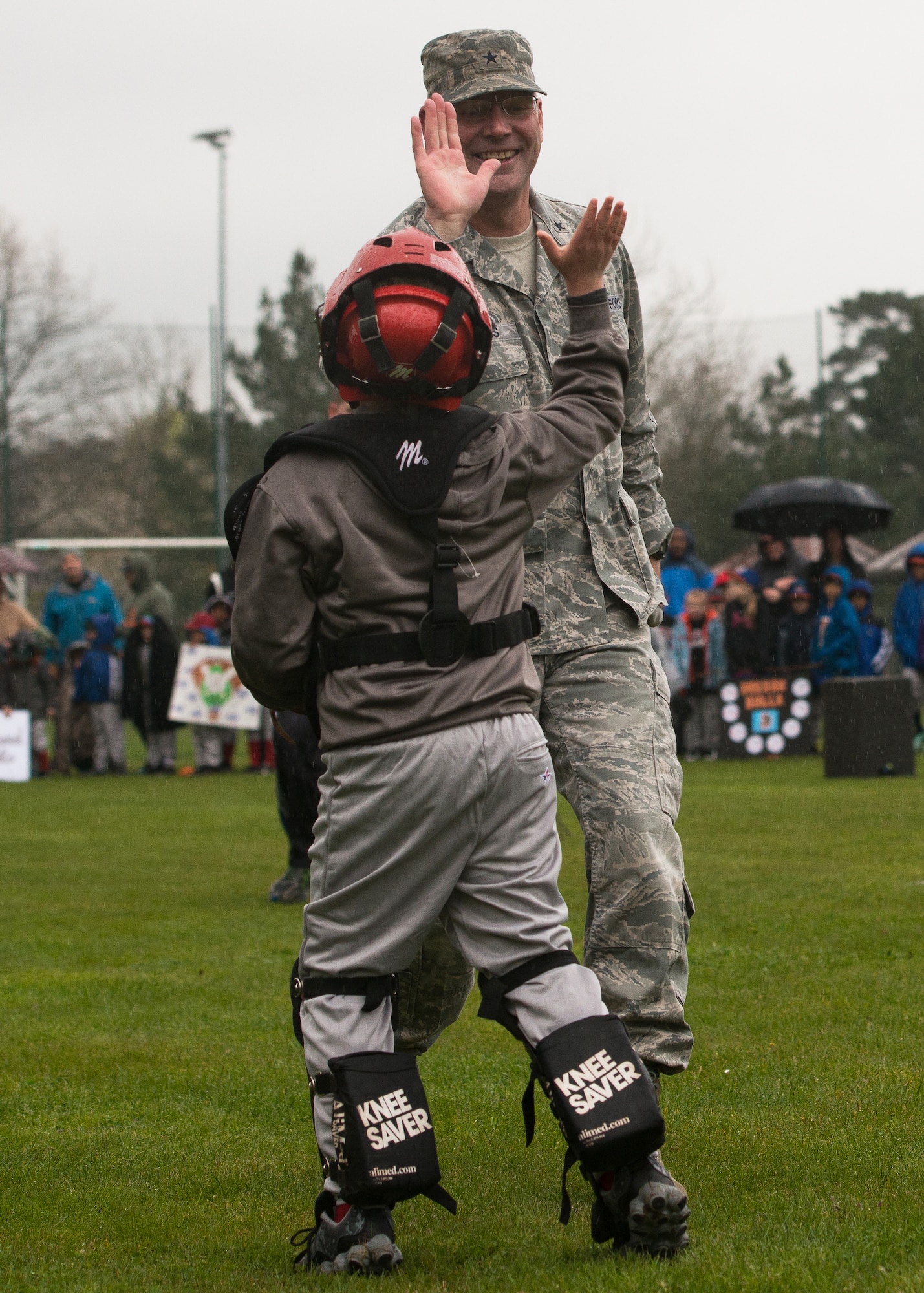 Brig. Gen. Jon T. Thomas, 86th Airlift Wing commander, gives a high-five to a young boy after he catches the ceremonial first pitch April 23, 2016, at Ramstein Air Base, Germany.The “first pitch” is  a longstanding ritual of American baseball in which a guest of honor throws the first pitch to launch the new tee-ball, softball or baseball season. (U.S. Air force photo/Airman 1st Class Lane T. Plummer)