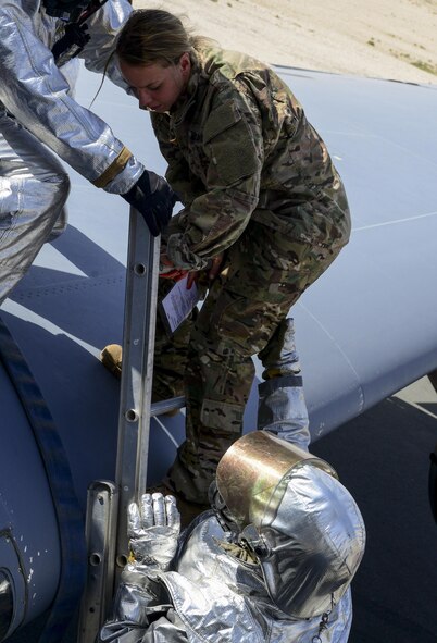 Members of the 379th Expeditionary Civil Engineer Squadron Fire Department escort a patient down from a wing of a KC-135 Stratotanker during a Major Accident Recovery Exercise April 26, 2016, at Al Udeid Air Base, Qatar. The exercise focused on mission assurance of command and control, interoperability, and how the wing and host nation function together. (U.S. Air Force photo/Senior Airman Janelle Patiño/Released)