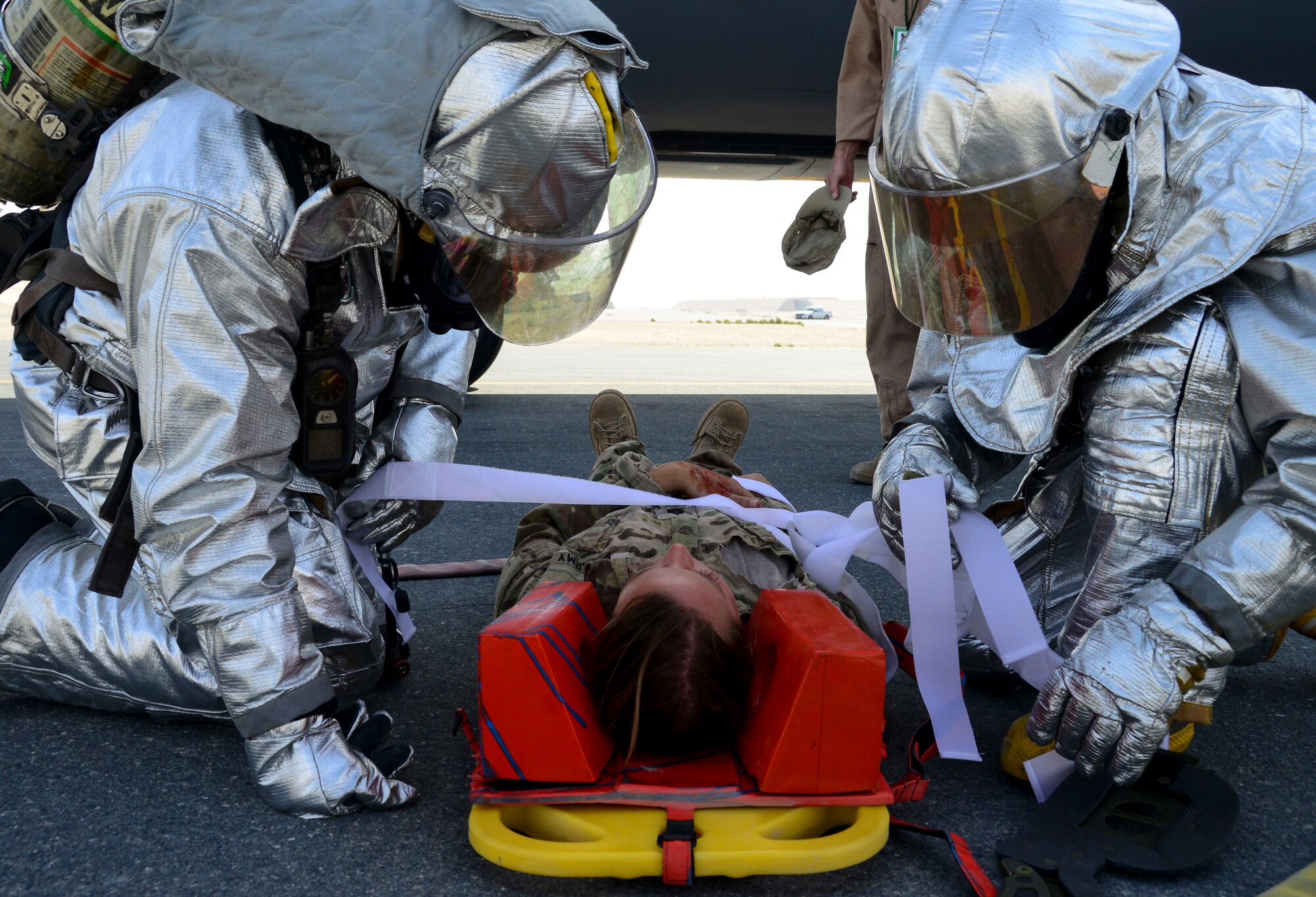 Members of 379th Expeditionary Civil Engineer Squadron Fire Department strap a patient safely into a spinal board during a Major Accident Recovery Exercise April 26, 2016, at Al Udeid Air Base, Qatar. The 379th Air Expeditionary Wing and host nation responders participated in the exercise to test their ability to respond to a major accident, which focused on mission assurance of command and control, interoperability, and how the wing and host nation function together. (U.S. Air Force photo/Senior Airman Janelle Patiño/Released)