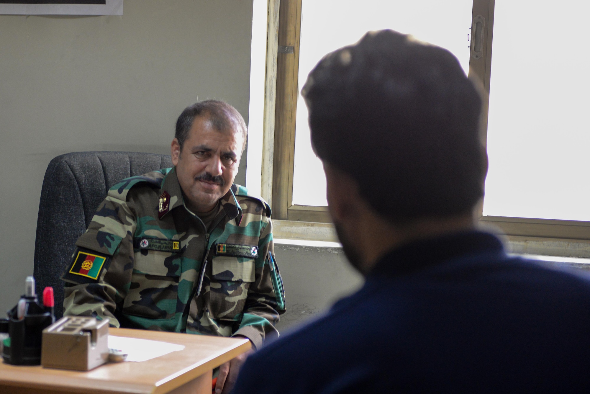 Afghan Air Force Lt. Col. Yaqubi Munir, lead recruiting officer, speaks to an interpreter at Kabul Air Wing, Afghanistan, Aug. 1, 2016. The AAF recruiters have a strong partnership with U.S. Airmen from Train, Advise, Assist Command-Air (TAAC-Air), and the two organizations are constantly fine-tuning the process to get the best and brightest young Afghans into the AAF. (U.S. Air Force photo by Tech. Sgt. Christopher Holmes) 