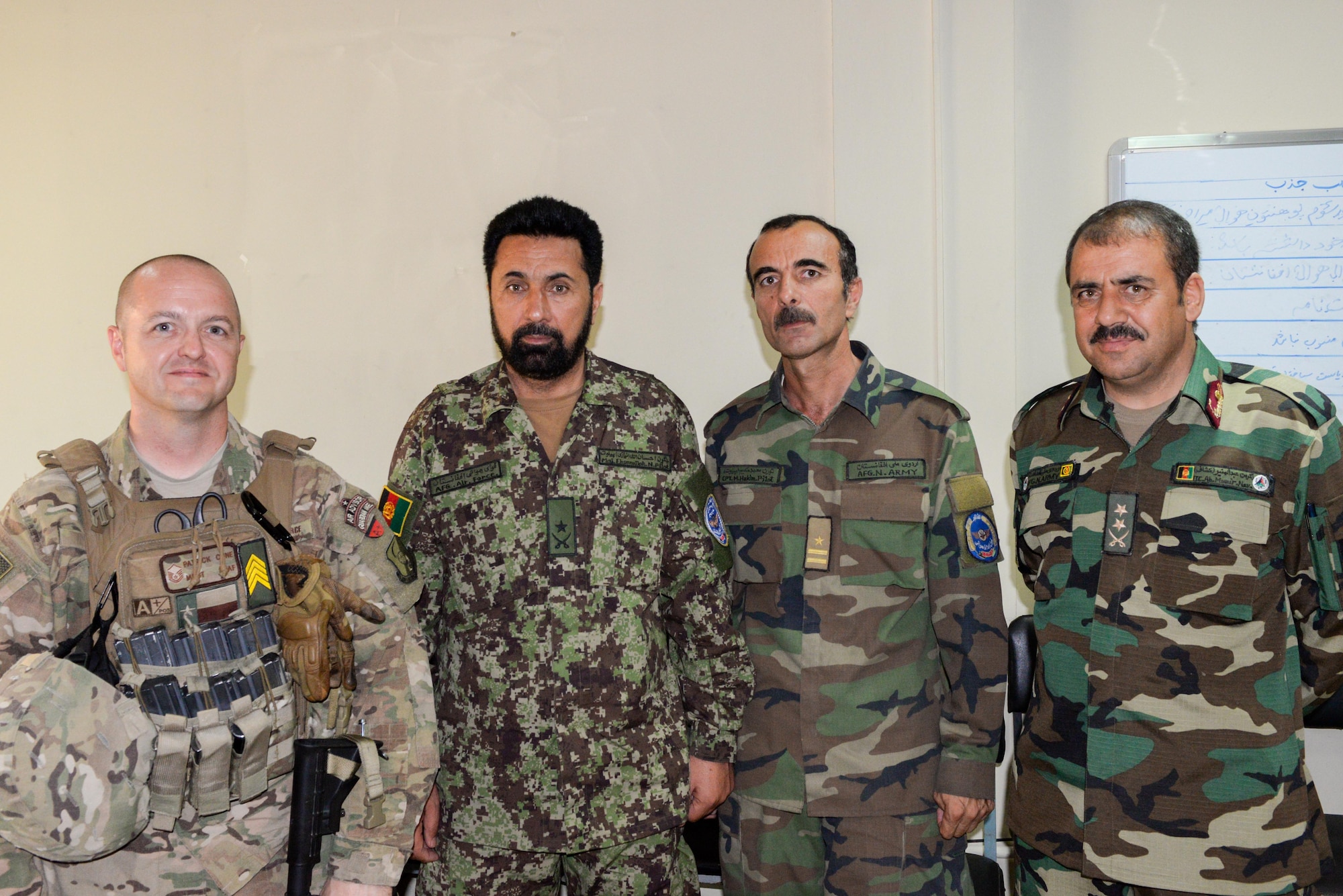 Master Sgt. Patrick Cone, Train, Advise, Assist Command-Air (TAAC-Air), poses with Afghan air force recruiters, Maj. Ehsanullah Niazay, Capt. Muhammed Hakim, and Lt. Col. Yaqubi Munir at Kabul Air Wing, Afghanistan, Aug. 1, 2016. Cone and the AAF members work shoulder to shoulder to come up with different ways to advertise and gain the interest of Afghans aged 18-26. (U.S. Air Force photo by Tech. Sgt. Christopher Holmes)