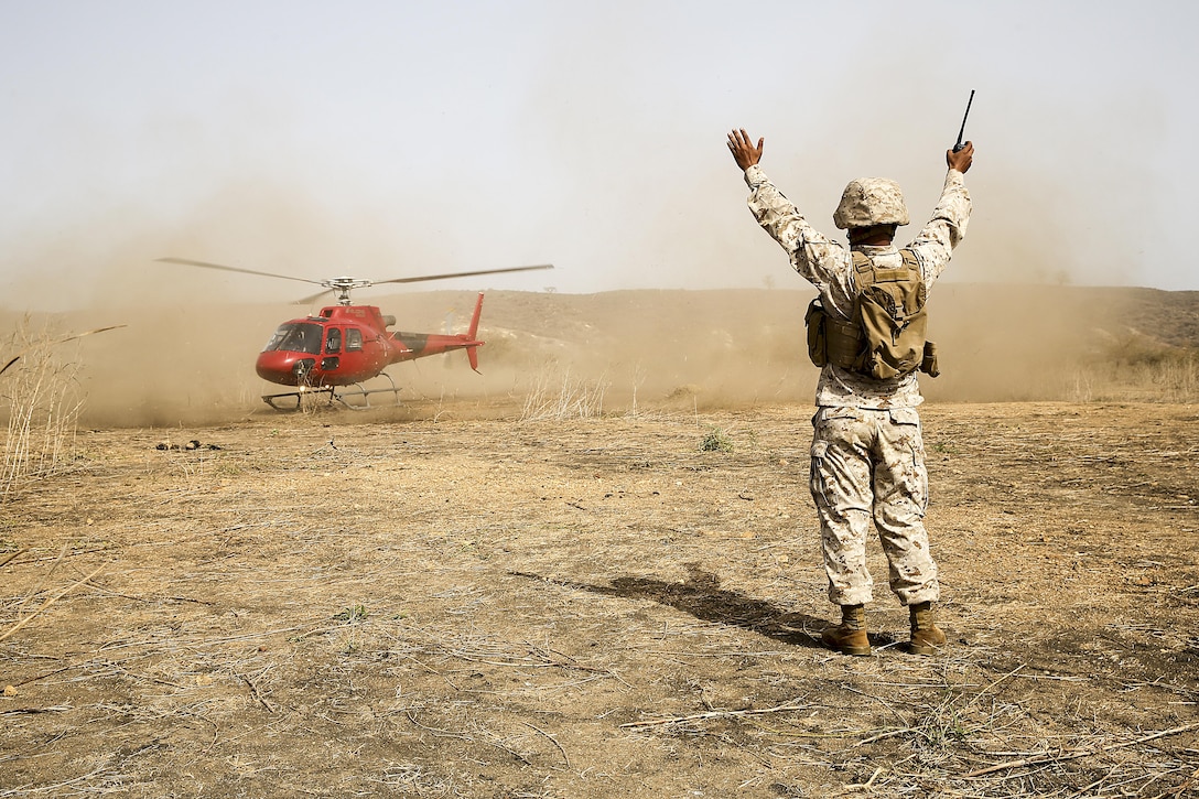 Staff Sgt. Jonathon St. Ann, a team chief with Special Purpose Marine Air-Ground Task Force Crisis Response-Africa, signals the appropriate landing zone to a helicopter during a medivac rehearsal with the Compagnie Fusilier de Marin Commando in Thies, Senegal, July 21, 2016. This is the first time Marines and the COFUMACO have used a helicopter for medical assistance during training in Senegal. This new capability saves valuable time should an injury occur during live-fire ranges. (U.S. Marine Corps photo by 1st Lt. Eric Abrams /released)