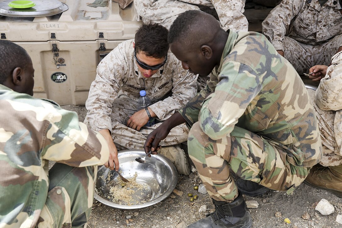 Sgt. Ryan Underwood, a rifleman with Special Purpose Marine Air-Ground Task Force Crisis Response-Africa, shares lunch with the Compagnie Fusilier de Marin Commando in Thies, Senegal, July 22, 2016. Marines and the COFUMACO conducted a three-week training exercise that included advanced combat firing techniques, a machine gun range and a live-fire platoon attack range. (U.S. Marine Corps photo by 1st Lt. Eric Abrams /released)