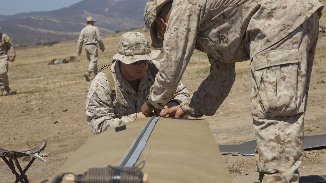 Cpl. Ryan T. Fry and Lance Cpl. Fabian J. Villegas, combat engineers with 1st Battalion, 5th Marine Regiment, 1st Marine Division, assemble a linear breaching charge with detonation cord at Camp Pendleton, California, July 26, 2016. A live-fire training exercise was conducted to give assaultmen and riflemen an opportunity to integrate with combat engineers and learn to build improvised breaching charges.