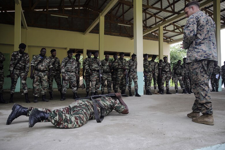 Cpl. John Floyd, a rifleman with Special Purpose Marine Air-Ground Task Force Crisis Response-Africa, watches a Cameroonian soldier with Forces Fusiliers Marins et Palmeurs de Combat conduct a low crawl while maintaining safe control of his weapon, during practical application in Limbé, Cameroon, June 28, 2016.  Marines share tactics, techniques and skills with the FORFUMAPCO soldiers to combat the illicit trafficking in Cameroon.  (U.S. Marine Corps photo by Cpl. Alexander Mitchell/released)