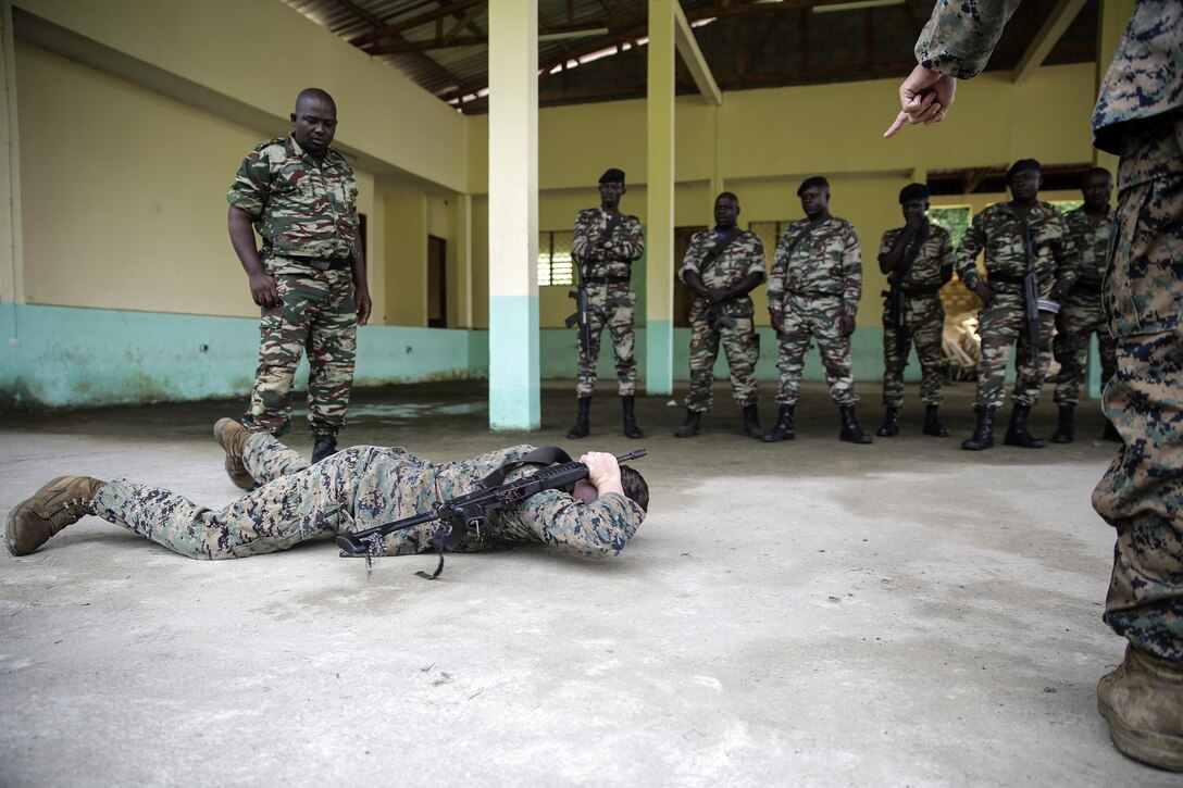 Lance Cpl. Dustin Kitts, a rifleman with Special Purpose Marine Air-Ground Task Force Crisis Response-Africa, shows a proper way to conduct a low crawl while maintaining safe control of the weapon for Cameroonian soldiers with Forces Fusiliers Marins et Palmeurs de Combat, in Limbé, Cameroon, June 28, 2016.  Marines share tactics, techniques and skills with the FORFUMAPCO soldiers to combat the illicit trafficking in Cameroon.  (U.S. Marine Corps photo by Cpl. Alexander Mitchell/released)