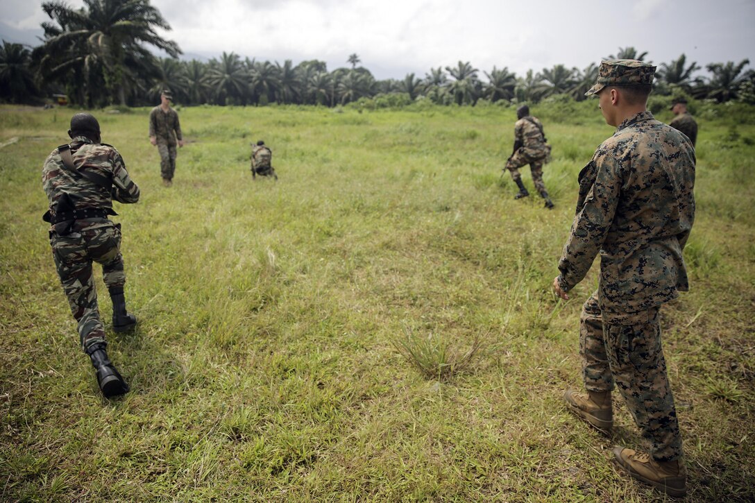 Cpl. Mitchell York, a rifleman with Special Purpose Marine Air-Ground Task Force Crisis Response-Africa, watches as Cameroonian soldiers with Forces Fusiliers Marins et Palmeurs de Combat, conduct buddy rushes in Limbé, Cameroon, June 28, 2016.  Marines share tactics, techniques and skills with the FORFUMAPCO soldiers to combat the illicit trafficking in Cameroon.  (U.S. Marine Corps photo by Cpl. Alexander Mitchell/released)