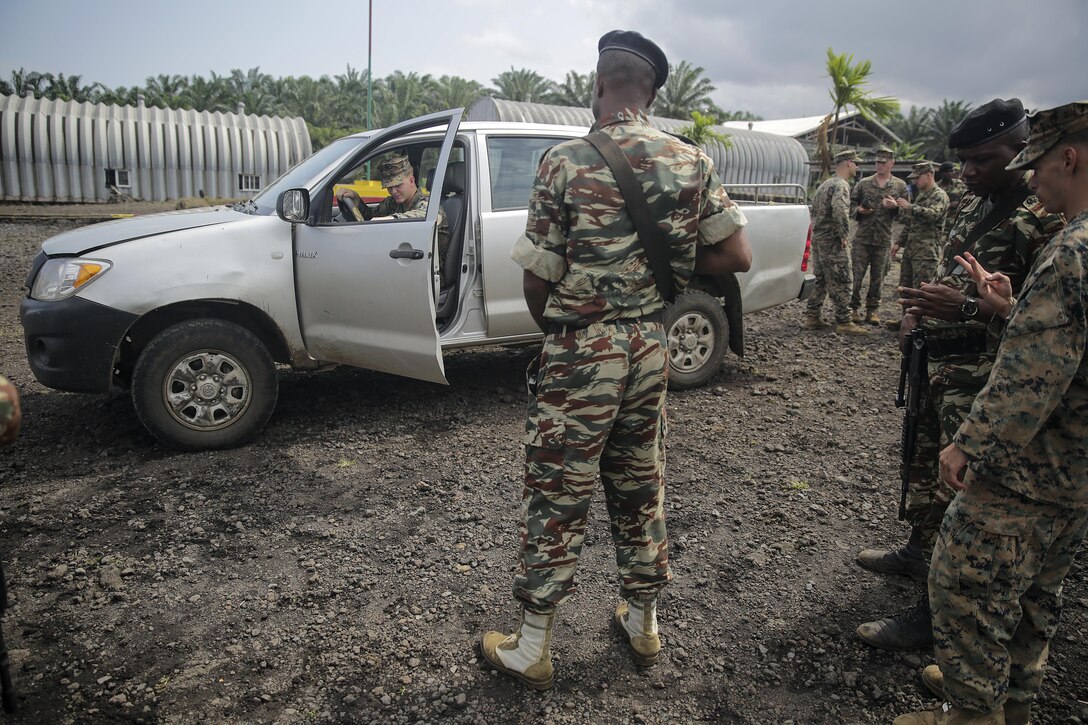 A Cameroonian soldier with Fusiliers Marins et Palmeurs de Combat, tells Lance Cpl. Dustin Kitts, a rifleman with Special Purpose Marine Air-Ground Task Force Crisis Response-Africa, to exit the truck during a vehicle search exercise in Limbé, Cameroon, June 30, 2016.  Marines share tactics, techniques and skills with the FORFUMAPCO soldiers to combat the illicit trafficking in Cameroon.  (U.S. Marine Corps photo by Cpl. Alexander Mitchell/released)