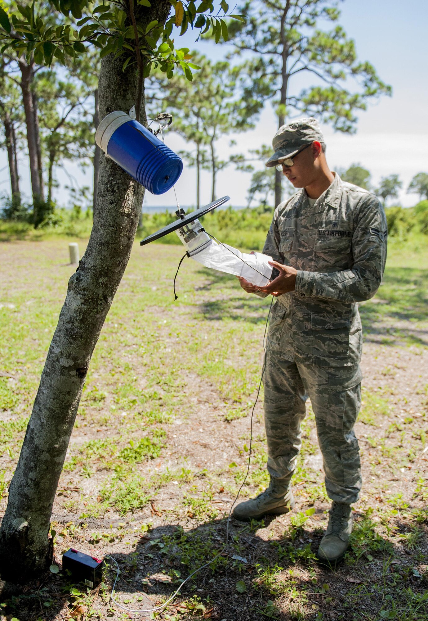 Airman 1st Class Stephen Nicer, 96th Aerospace Medicine Squadron public health technician, checks the mosquito trap near base housing July 20 at Eglin Air Force Base Fla. Nicer ensures the trap functions properly. The trap is used to catch a variety of mosquitoes during the evening hours. (U.S. Air Force photo/Ilka Cole)