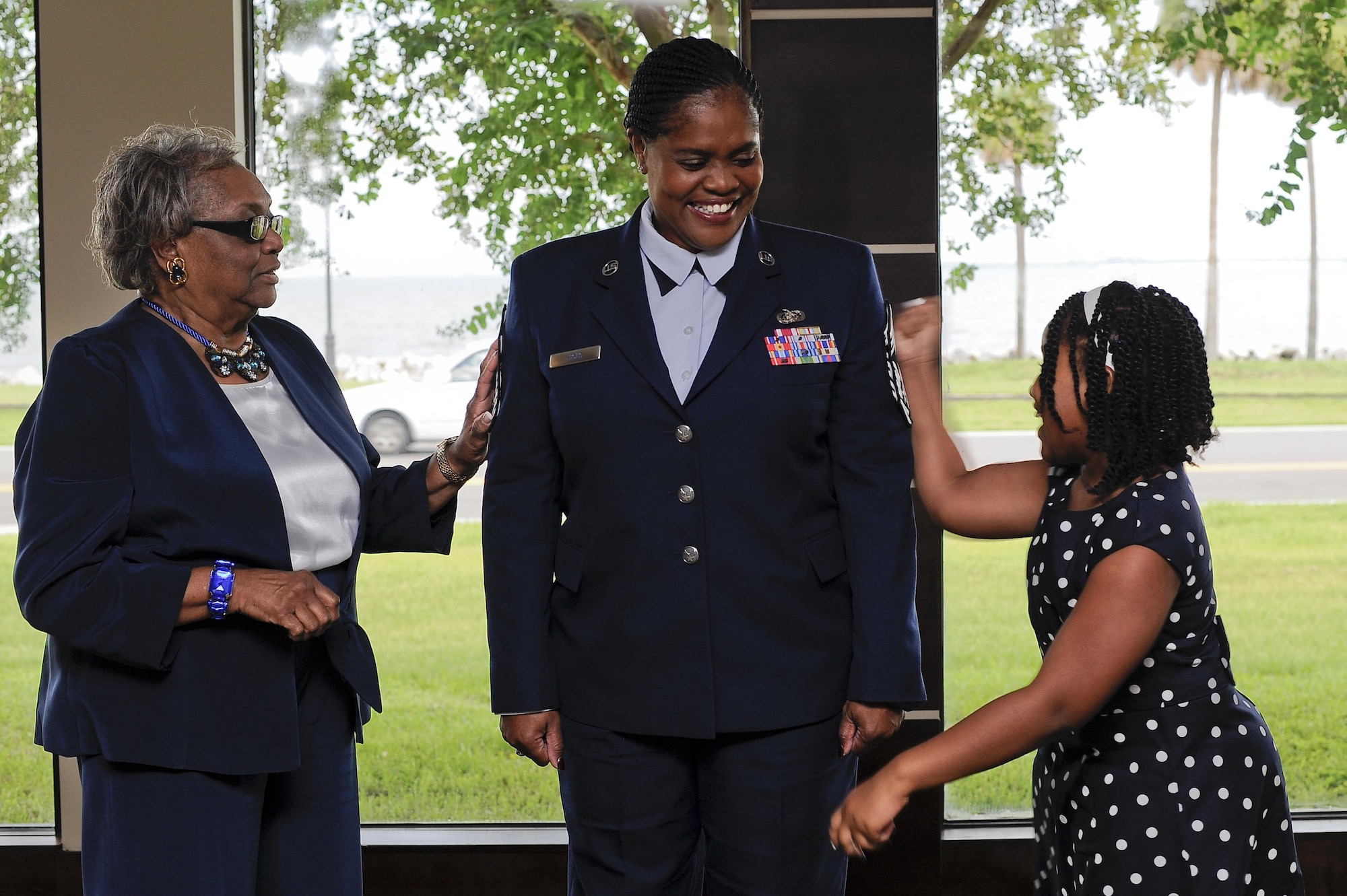 Chief Master Sgt. Lessie Hicks, mission support chief with the 290th Joint Communications Support Squadron (JCSS), center, gets her chief stripes tacked on by her family, July 29, 2016, at MacDill Air Force Base, Fla. Hicks is the first African-American and female chief at the 290th JCSS. (U.S. Air Force photo by Airman 1st Class Mariette Adams)