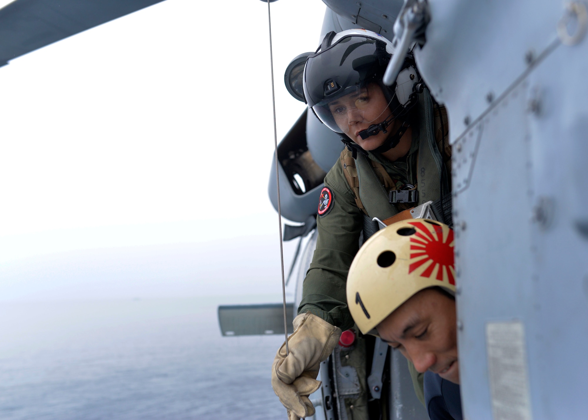 U.S. Navy Naval Aircrewman (Helicopter) 1st Class Calah Sanchez, top, assigned with the Helicopter Sea Combat Squadron 25, works with a Japanese Maritime Self-Defense Force member, bottom, during the Mine Countermeasures Exercise 2JA near the region surrounding Misawa Air Base, Japan, July 20, 2016. The annual bilateral exercise is held between the U.S. Navy and JMSDF to strengthen interoperability and increase proficiencies in mine countermeasure operations. (U.S. Navy photo by Mass Communication Specialist 2nd Class Samuel Weldin)
