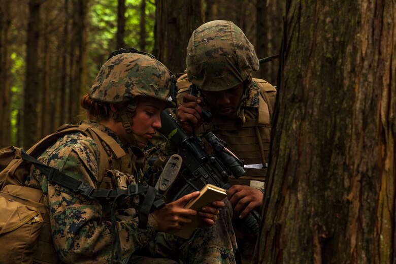 U.S. Marine Corps Cpl. Kassandra Gonzalez, left, Headquarters and Service Company, air base ground defense noncommissioned officer, assists Lance Cpl. Maliek Morgan, a field radio operator with Marine Wing Support Squadron (MWSS) 171 stationed at Marine Corps Air Station Iwakuni, Japan, radio-in after receiving contact from a simulated enemy during Exercise Eagle Wrath 2016 at Combined Arms Training Center Camp Fuji, July 28, 2016. During the culminating event, Marines established a mock air base including a landing zone and refueling point, constructed defensive and machine-gun positions, and conducted convoys and patrols over the course of four days. (U.S. Marine Corps photo by Lance Cpl. Aaron Henson)