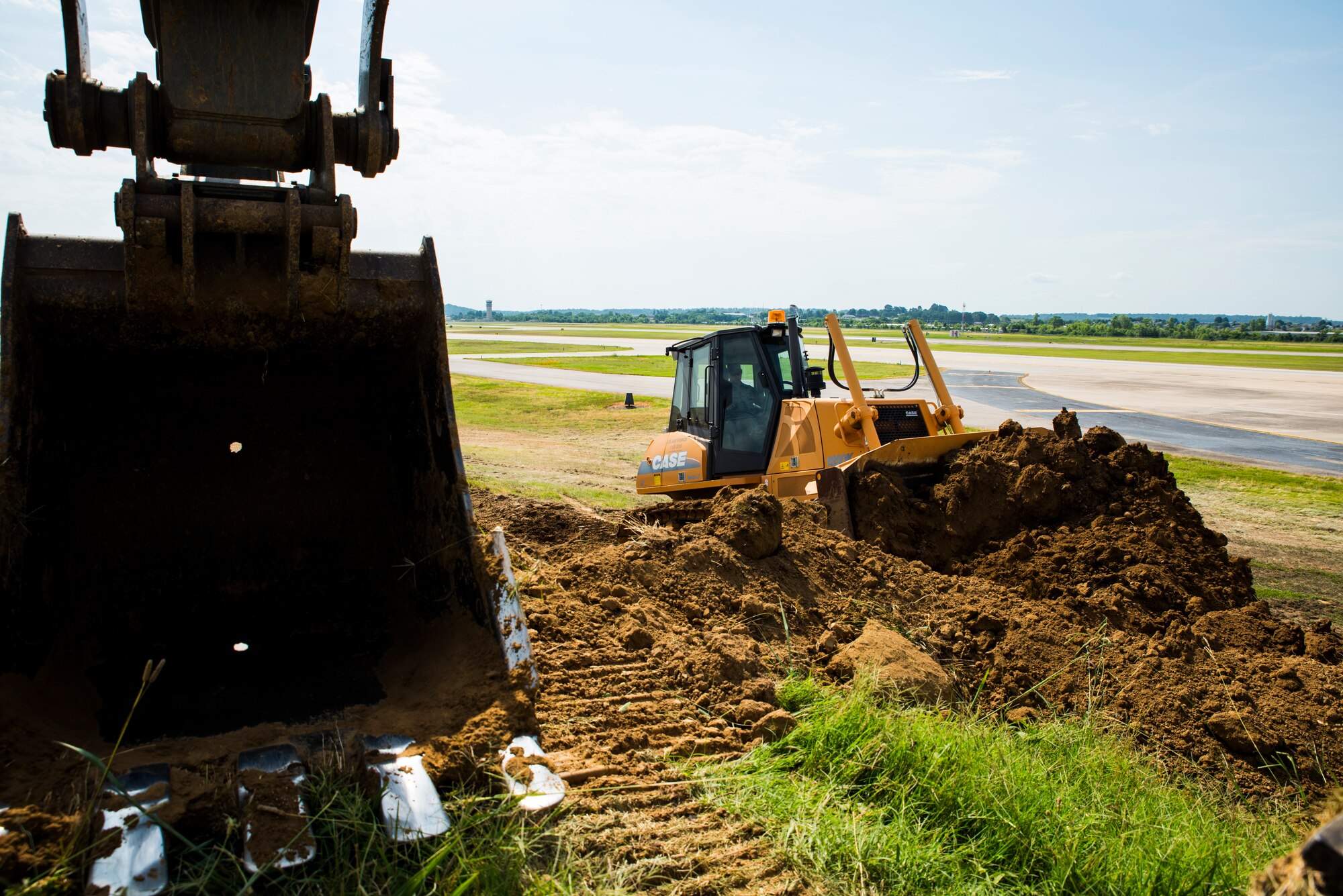 Staff Sgt. Shannon Feliccia, 188th Civil Engineer Squadron heavy equipment operator, operates the crawl tractor and Senior Airman Adam Brannon, 188th CES heavy equipment operator, operates an excavator June 24, 2016, to remove dirt from the west hammerhead arm dearm berm at Ebbing Air National Guard Base, Fort Smith, Ark. The 188th CES removed 1,400 cubic yards of dirt by the end of the weekend and plan to remove the rest of the berm in August. (U.S. Air National Guard photo by Senior Airman Cody Martin/Released)