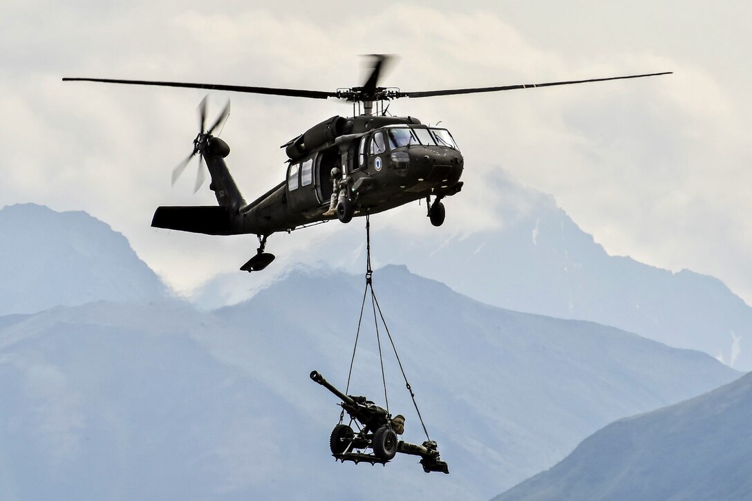 A UH-60 Black Hawk helicopter sling-loads a 105 mm howitzer during the Arctic Thunder Open House at Joint Base Elmendorf-Richardson, Alaska, July 31, 2016. The biennial event is one of the premier aerial demonstrations in the world. The helicopter is assigned to the Alaska Army National Guard. Air Force photo by Justin Connaher