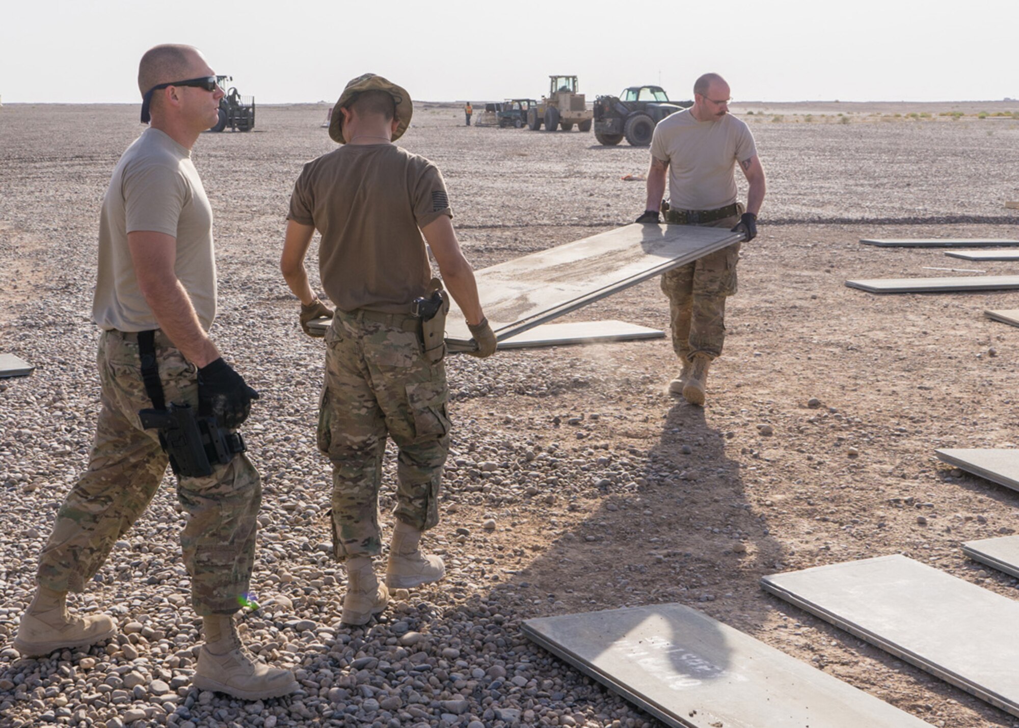 Tech. Sgt. Dan Zimmerman (right) and Senior Airman Thet Tun (left) carry a piece of AM2 matting material, Camp Dwyer, Afghanistan, July, 12, 2016. Zimmerman and Tun spread out AM2 matting in order to build a helicopter landing zone to support the medical facility at Camp Dwyer. (Courtesy photo by 451 Air Expeditionary Support Squadron)