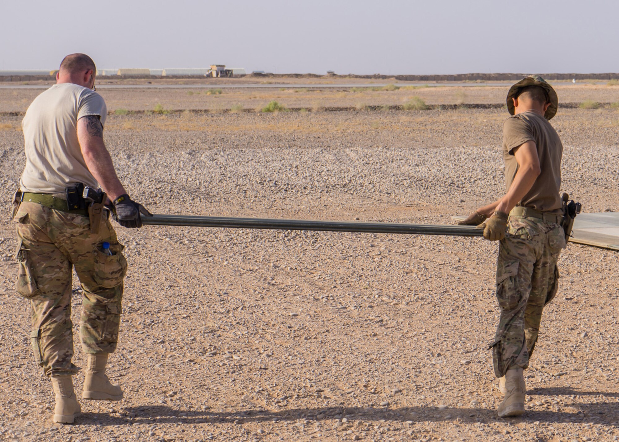 Tech. Sgt. Dan Zimmerman (left) and Senior Airman Thet Tun (right) carry a piece of AM2 matting material, Camp Dwyer, Afghanistan, July, 12, 2016. Zimmerman and Tun constructed a 100’ x 100’ helicopter landing zone out of AM2 matting to support the medical facility at Camp Dwyer. (Courtesy photo by 451 Air Expeditionary Support Squadron)