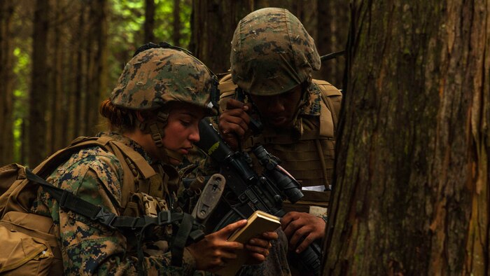 U.S. Marine Corps Cpl. Kassandra Gonzalez, left, Headquarters and Service Company, air base ground defense noncommissioned officer, assists Lance Cpl. Maliek Morgan, a field radio operator with Marine Wing Support Squadron 71 stationed at Marine Corps Air Station Iwakuni, Japan, radio-in after receiving contact from a simulated enemy during Exercise Eagle Wrath 2016 at Combined Arms Training Center Camp Fuji,Japan, July 28, 2016. During the culminating event, Marines established a mock air base including a landing zone and refueling point, constructed defensive and machine-gun positions, and conducted convoys and patrols over the course of four days. 