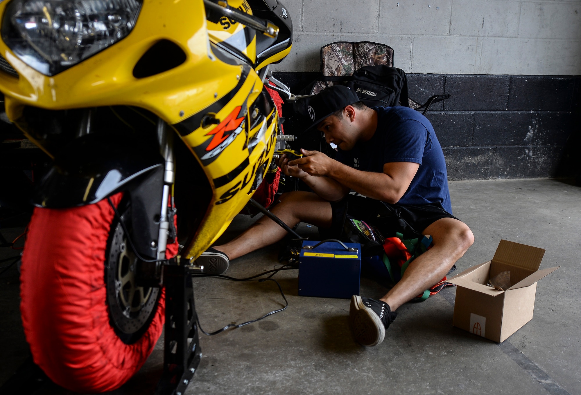 A U.S. Air Force Airman works on his motorcycle in a pit garage during the Military Track Day July 26, 2016, at Snetterton Circuit in Norwich, England. Before riders could enter the track their motorcycles had to pass a decibel test and inspection. (U.S. Air Force photo by Staff Sgt. Micaiah Anthony)