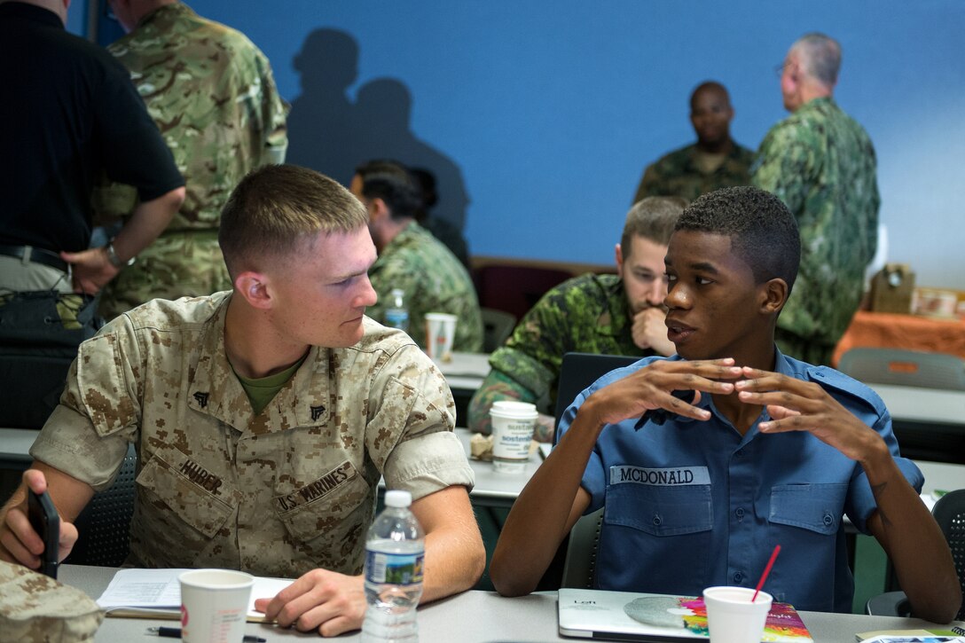 A U.S. Marine, left, talks to another service member participating in the North America Information Operations/Combat Camera Exercise during a briefing at Fort A.P. Hill, Va., July 26, 2016. DoD photo by EJ Hersom