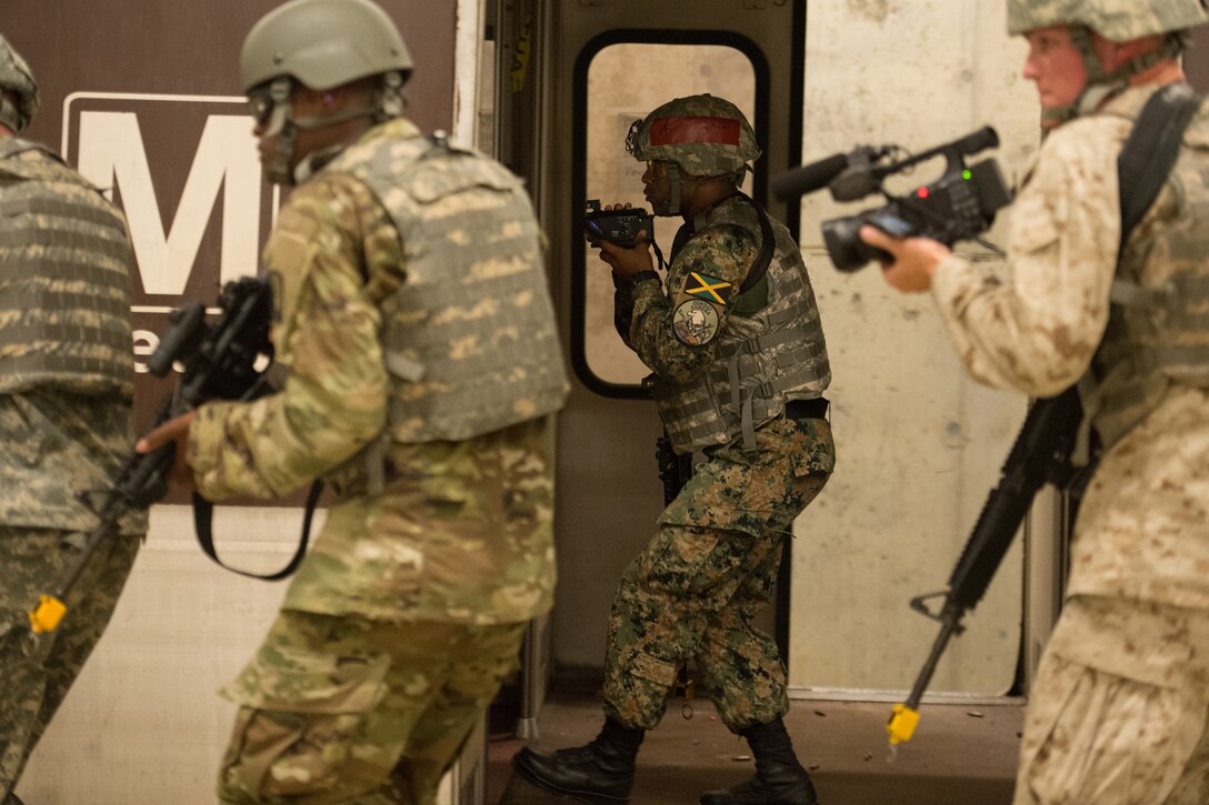 Jamaica Defense Force Cpl. Darren Beckles, center, documents a simulated battle inside a subway car at a training facility at Fort A.P. Hill, Va., July 27, 2016, during the North America Information Operations/Combat Camera Exercise. DoD photo by EJ Hersom