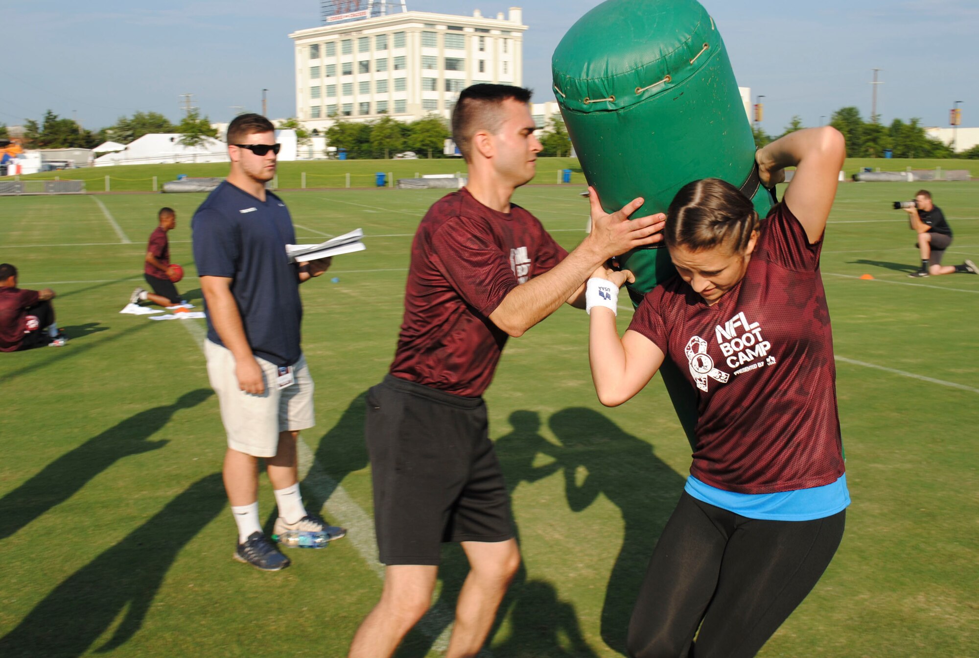 U.S. Air Force Staff Sgt. Chloee Moore, 733rd Logistics Readiness Squadron fuels distribution supervisor, hands a tackling dummy to Senior Airman Caleb Jones, 633rd Contracting Squadron contract specialist, during the mini boot camp July 28, 2016 at Bon Secours Washington Redskins Training Center in Richmond, Va. The 10 teams competed in five skills events for the title of NFL Boot Camp champions and tickets to a Salute to Service game Nov, 20, 2016 at Fed Ex Field. (U.S. Air Force photo by Tech. Sgt. Darnell T. Cannady)