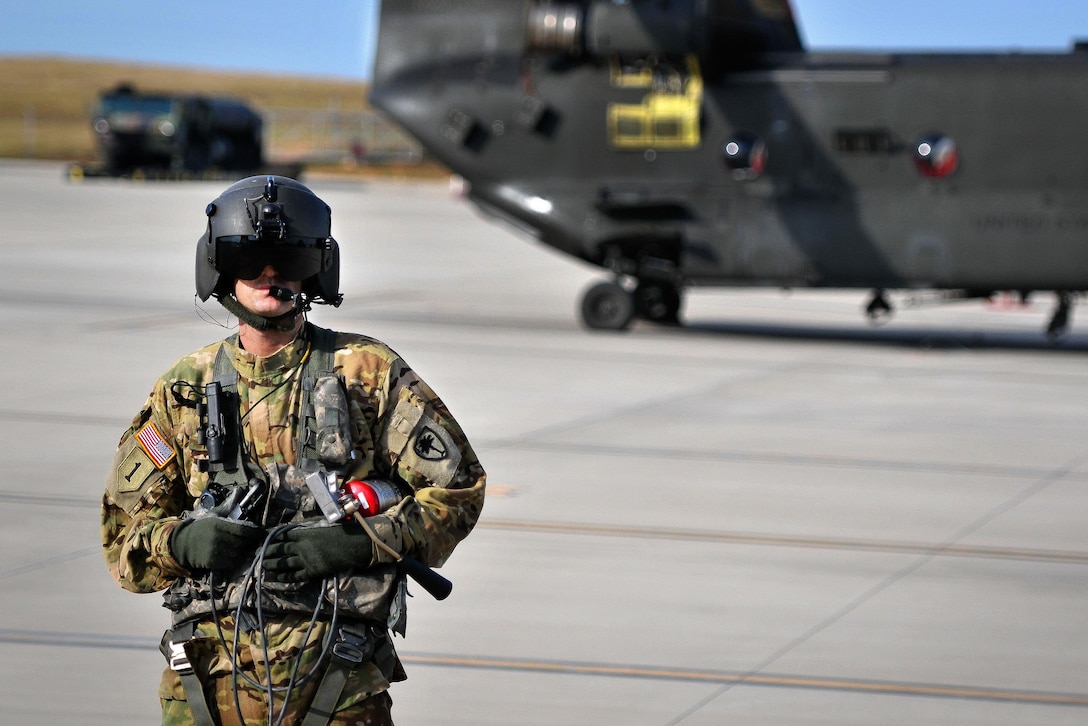 Army Sgt. Ira J. Duville communicates with the pilots inside a CH-47D Chinook helicopter before lthey participate in a scheduled training mission over Greenville, S.C.,, July 22, 2016. Duville is a crew chief is assigned to the South Carolina Army National Guard’s Headquarters Company, 2nd Battalion, 151st Security Support Aviation Battalion. Army National Guard photo by Staff Sgt. Roby Di Giovine