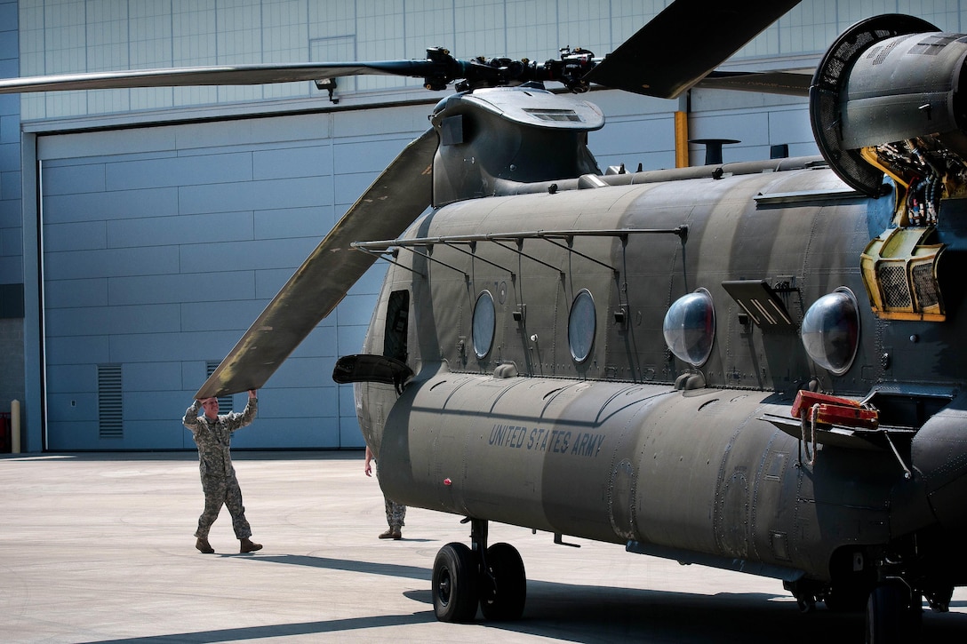 Army crew chiefs check the front rotor blades on a CH-47D Chinook helicopter before a scheduled training mission over Greenville, S.C., July 22, 2016. The crew chiefs are assigned to the South Carolina Army National Guard’s Headquarters Company, 2nd Battalion, 151st Security Support Aviation Battalion. Army National Guard photo by Staff Sgt. Roby Di Giovine