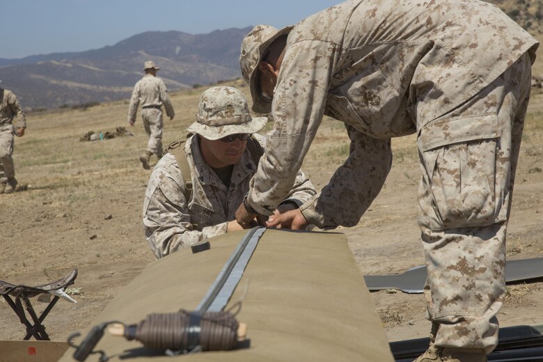 Cpl. Ryan T. Fry and Lance Cpl. Fabian J. Villegas, combat engineers with 1st Battalion, 5th Marine Regiment, 1st Marine Division, assemble a linear breaching charge with detonation cord at Camp Pendleton, Calif., July 26, 2016. A live-fire training exercise was conducted to give assaultmen and riflemen an opportunity to integrate with combat engineers and learn to build improvised breaching charges. (U.S. Marine Corps Photo by Lance Cpl. Bradley J. Morrow)