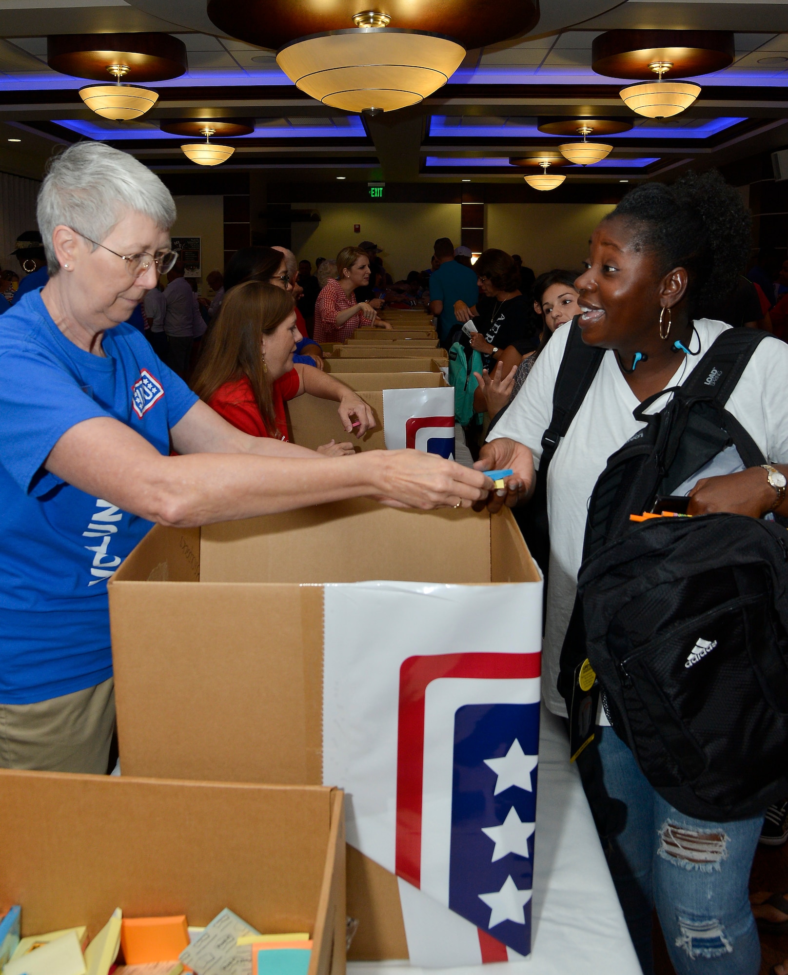 Barbara Szatkowski, a volunteer from the United Service Organization, hands school supplies to Master Sgt. Widlene Harrell, J1 superintendent assigned to Special Operations Command Central, during the Back to School Fair at MacDill Air Force Base, Fla., July 30, 2016. Participating families received backpacks, school supplies and resources, and giveaways from community agencies and sponsors. (U.S. Air Force photo by Staff Sgt. Shandresha Mitchell)