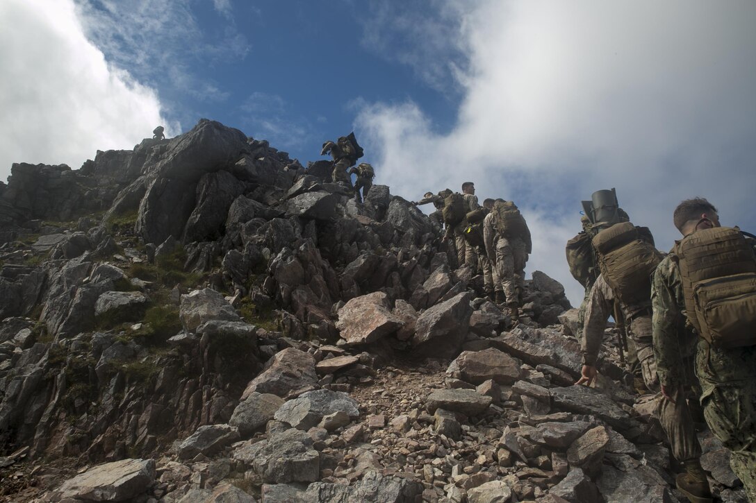 U.S. Marines, sailors and Royal Commandos climb to the summit of a mountain, July 20, 2016, in the Scottish Highlands, Inverness, Scotland, during the mountain training phase of the Tartan Eagle 16 exercise. The mountain training phase consisted of learning mountain survival skills, map reading and how to successfully traverse a mountain. Tartan Eagle is an annual training event that began in 1994. Marines and sailors with Marine Corps Security Force Regiment trained alongside 43 Command Fleet Protection Group Royal Commandos to exchange best security and training practices and to foster good relations between the two commands. The exercise allowed for the exchange of tactics, techniques and procedures in the security of strategic assets. (Official Marine Corps photo by Sgt. Calvin Shamoon/ Released)