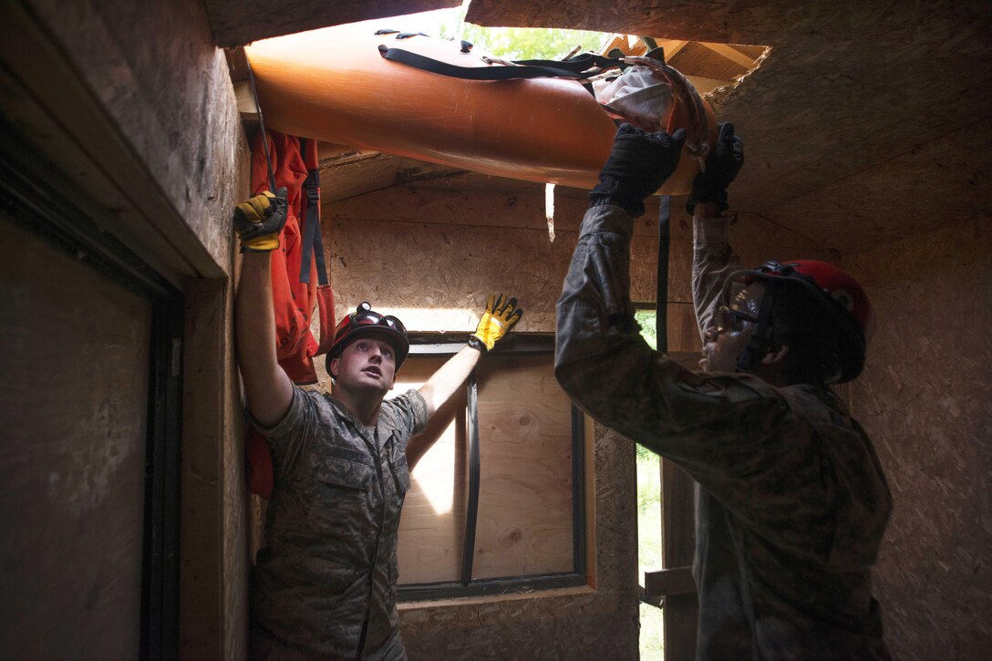 Air Force Senior Airman Aaron Strande, left, and Army Spc. Larry Joseph stabilize a mock patient they have moved through an opening on a roof during Vigilant Guard 2016 at Camp Ethan Allen Training Site in Jericho, Vt., July 31, 2016. Strande is a search and rescue medic assigned to the Massachusetts Air National Guard’s 102nd Intelligence Wing. Joseph is assigned to the Massachusetts Army National Guard’s 181st Engineer Battalion. Air National Guard photo by Airman 1st Class Jeffrey Tatro