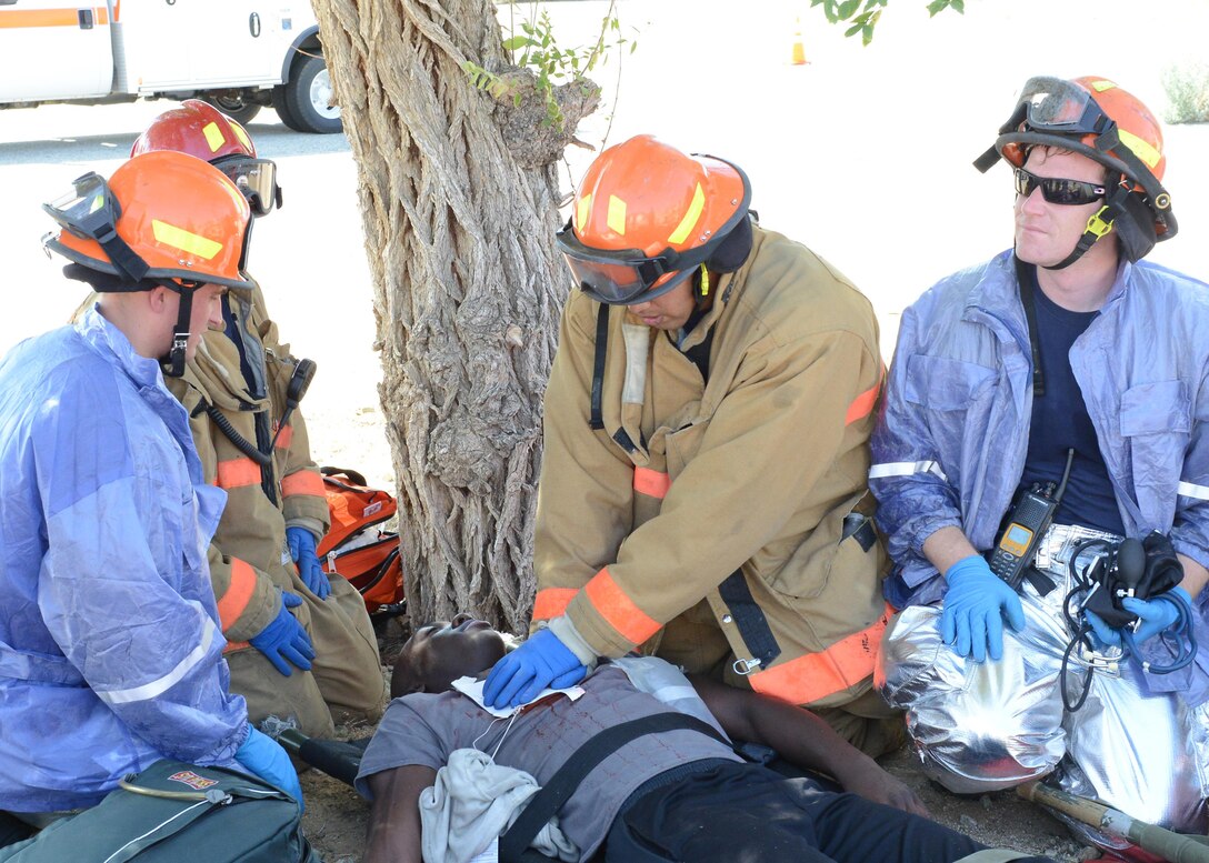 Edwards AFB Fire Department treats a "wounded" patient under a tree after being removed from Bldg. 2850 Aug. 1. Exercise Desert Wind 16-05 tested the base's response capabilities to an active shooter scenario. (U.S. Air Force photo by Kenji Thuloweit)
