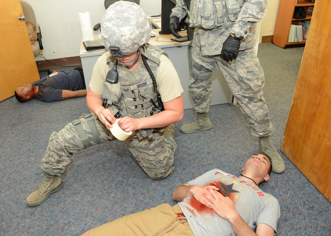 Staff Sgt. Stephanie Grebe, 412th Security Forces Squadron, tends to a victim of a simulated shooting Aug. 1 at Bldg. 2850. The 412th Medical Group has a moulage team who dressed up wounds on 22 actors for Exercise Desert Wind 16-05. The scenario for this exercise was an active shooter who shot 22 people and killed 13. (U.S. Air Force photo by Kenji Thuloweit)