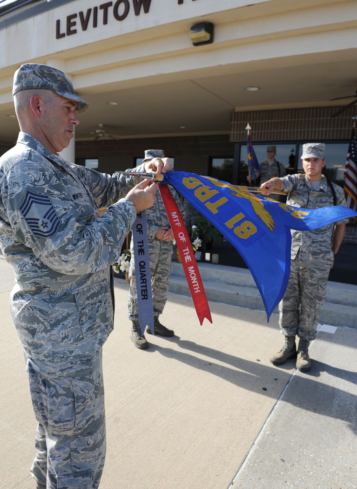 Chief Master Sgt. Robert Winters, 81st Training Group superintendent, attaches a Military Training Flight of the Month to the 336th Training Squadron guidon for their second-quarter win during the 81st Training Group Dragon Recognition Ceremony on the drill pad at the Levitow Training Support Facility July 28, 2016, on Keesler Air Force Base, Miss. The monthly event also recognized the Airman of the Month for June, the 2016 second quarter Military Training Flight and military training leader dragon award winner as well as Airmen promotees. (U.S. Air Force photo by Kemberly Groue/Released)