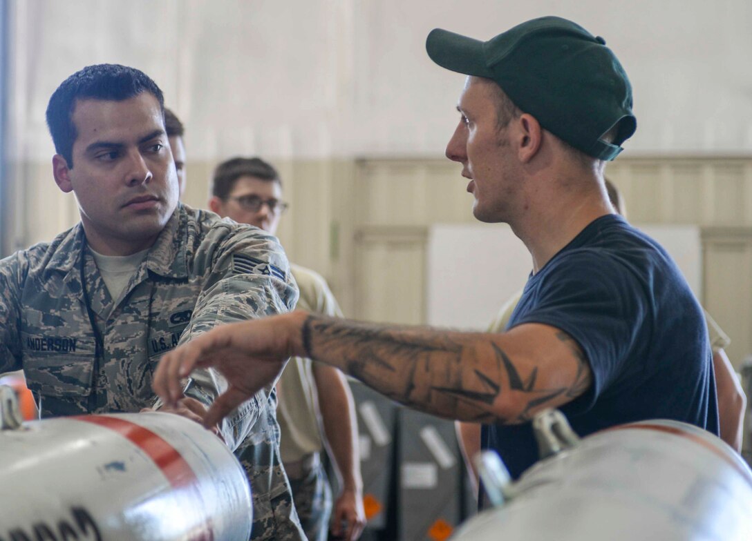 Staff Sgt. Anthony Anderson, a conventional maintenance crew chief and munitions inspector assigned to the 28th Munitions Squadron, receives direction from Petty Officer Second Class Nick Werner, a minesman assigned to the Navy Munitions Command (NMC) Atlantic Unit, Charleston, S.C., at Ellsworth Air Force Base (AFB), S.D., July 20, 2016. Sailors from the NMC Unit Charleston were sent to Ellsworth to train Airmen on building mines for the B-1 bomber to deploy. (U.S. Air Force photo by Airman 1st Class Sadie Colbert)