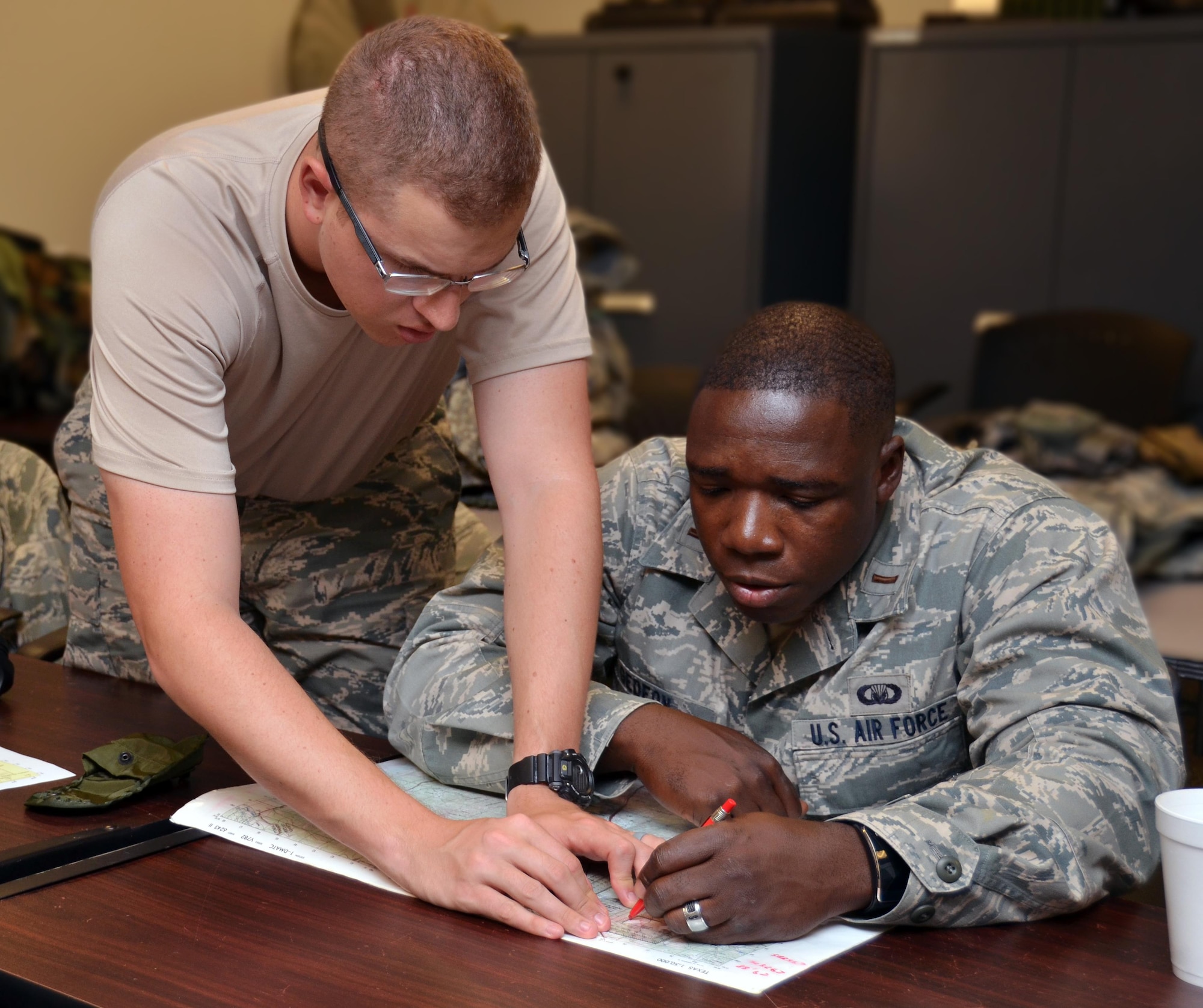 2nd Lieutenant Nathaniel Cantu helps 2nd Lieutenant Willy Gedeon figure out how to plot coordinates onto a map at Robins Air Force Base, Georgia, July 25, 2016. The candidates are participating in the Air Force Reserve Command Chaplain Candidate Intensive Interview program which aims to provide an extensive overview of what the Air Force Reserve mission is as well as a broad overview of the military chaplain corps. During the last week of the program, the candidates were immersed in fast-paced mobility training conducted by active-duty instructors from the 5th Combat Communications Squadron Support. (U.S. Air Force photo/Tech. Sgt. Kelly Goonan)