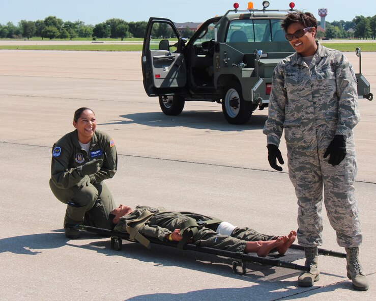 Sharing their load with a smile and a great attitude, even in the summer heat, 932nd Aeromedical Evacuation Squadron members Tech. Sgt. Deshae Clinton (kneeling), and Master Sgt. Kelly Willis, prepare to load up a simulated patient during a C-130 loading procedure.  932nd AW and 908th Airlift Wing Aeromedical Evacuation Squadrons trained together, giving mutually beneficial training time to both aircrews.  (U.S. Air Force photo by Maj. Stan Paregien)
