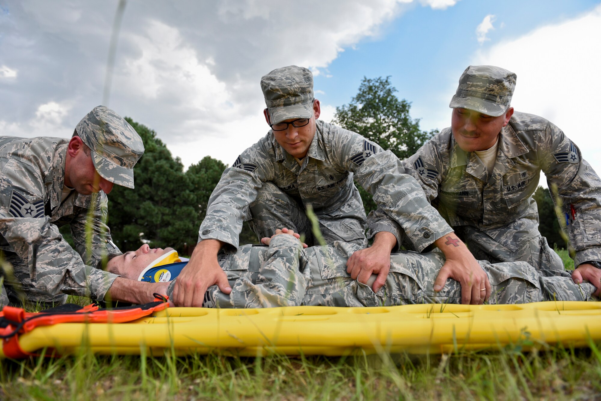 PETERSON AIR FORCE BASE, Colo. – Staff Sgt. Corey Czajka, 21st Aerospace Medicine Squadron independent duty medical technician, center, prepares to roll a patient onto a long backboard during a training exercise at Peterson Air Force Base, Colo., July 28, 2016. Czajka used the same skills practiced during this exercise as a real-world accident a few weeks ago when he stabilized a patient of a vehicle rollover until Colorado Springs paramedics arrived, then continued to assist them. (U.S. Air Force photo by Senior Airman Rose Gudex)