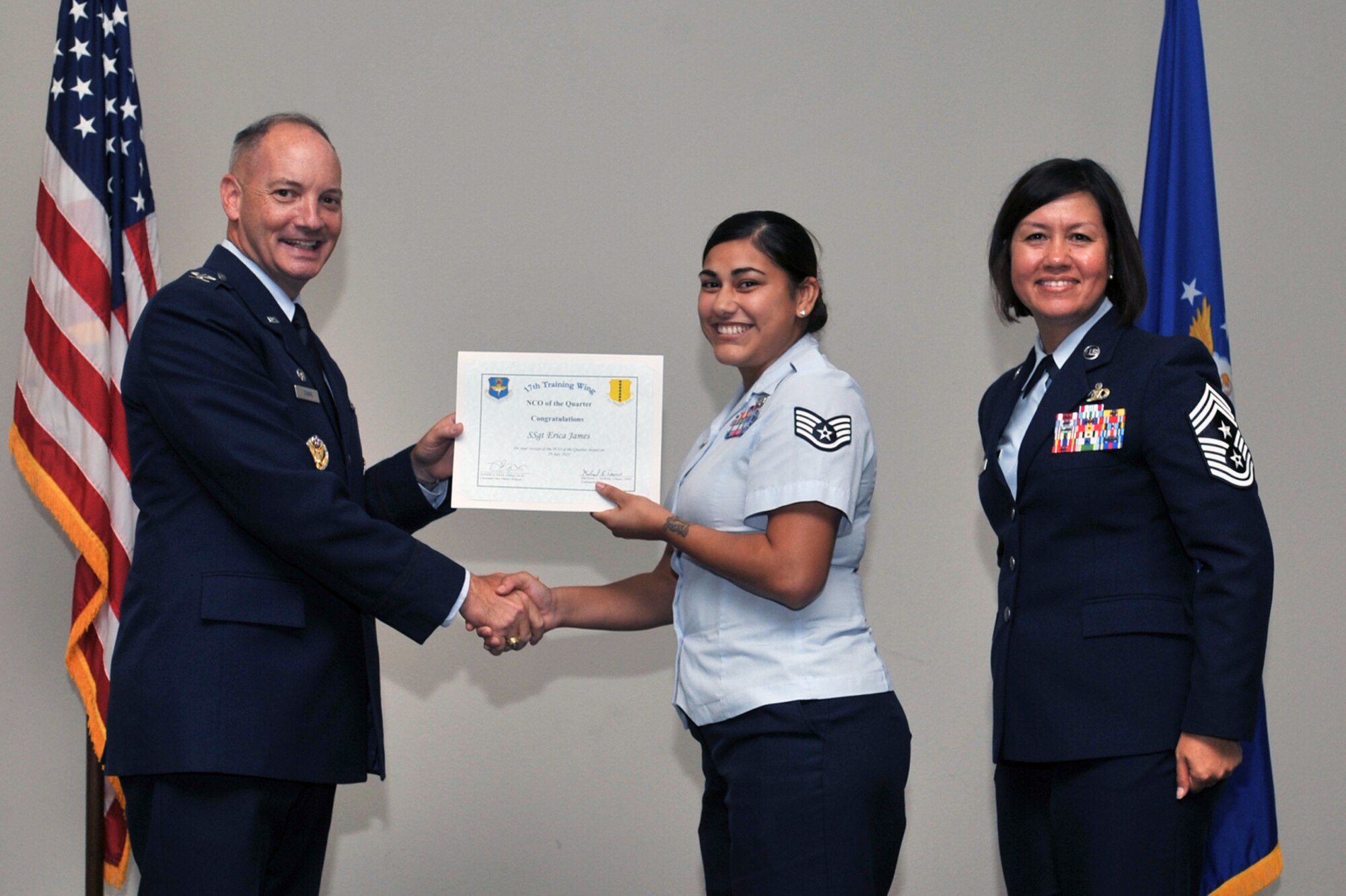 U.S. Air Force Col. Michael Downs, 17th Training Wing Commander, and Chief Master Sgt. JoAnne Bass, 17th Training Wing Command Chief, present the NCO of the Quarter award to Staff Sgt. Erica James, 17th Communications Squadron, during the wing quarterly awards ceremony at the Event Center on Goodfellow Air Force Base, Texas, July 29, 2016. (U.S. Air Force photo by Staff Sgt. Laura R. McFarlane/Released)