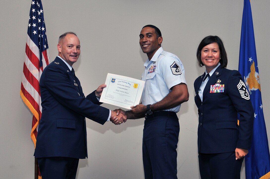 U.S. Air Force Col. Michael Downs, 17th Training Wing Commander, and Chief Master Sgt. JoAnne Bass, 17th Training Wing Command Chief, present the 17th Training Wing Senior NCO of the Quarter award to Master Sgt. Aaron Myers, 17th Communications Squadron, during the wing quarterly awards ceremony at the Event Center on Goodfellow Air Force Base, Texas, July 29, 2016. (U.S. Air Force photo by Staff Sgt. Laura R. McFarlane/Released)