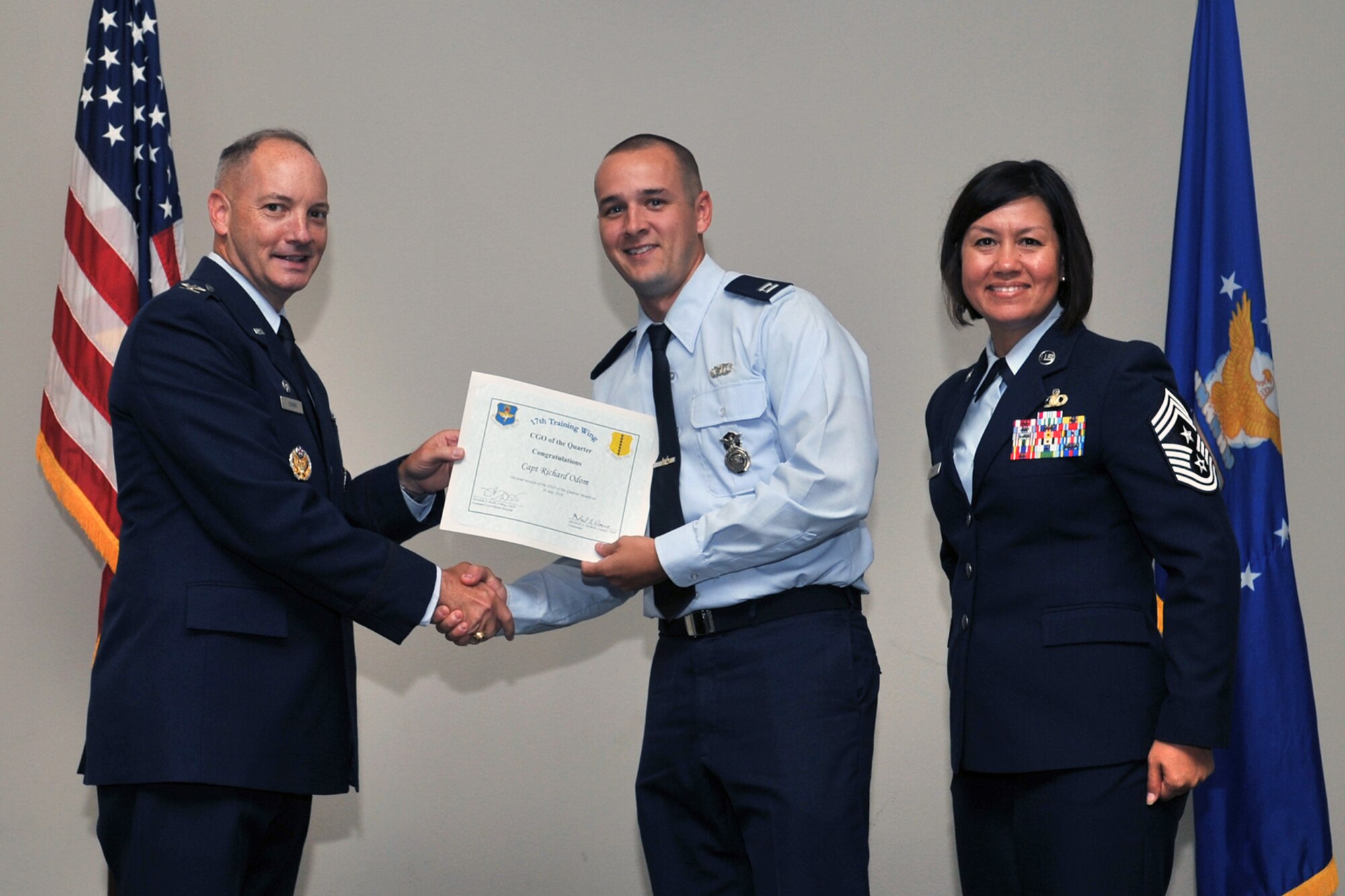 U.S. Air Force Col. Michael Downs, 17th Training Wing Commander, and Chief Master Sgt. JoAnne Bass, 17th Training Wing Command Chief, present the Company Grade Officer of the Quarter award to Capt. Richard Odom, 17th Security Forces Squadron, during the wing quarterly awards ceremony at the Event Center on Goodfellow Air Force Base, Texas, July 29, 2016. (U.S. Air Force photo by Staff Sgt. Laura R. McFarlane/Released)
