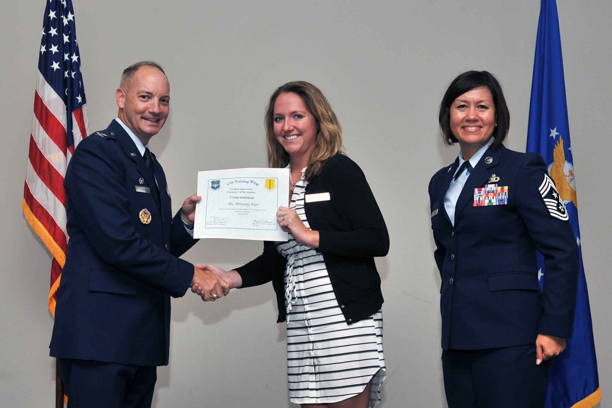 U.S. Air Force Col. Michael Downs, 17th Training Wing Commander, and Chief Master Sgt. JoAnne Bass, 17th Training Wing Command Chief, present the 17th Training Wing Civilian Category I Supervisory of the Quarter award to Brittany Furr, 17th Force Support Squadron, during the wing quarterly awards ceremony at the Event Center on Goodfellow Air Force Base, Texas, July 29, 2016. (U.S. Air Force photo by Staff Sgt. Laura R. McFarlane/Released)