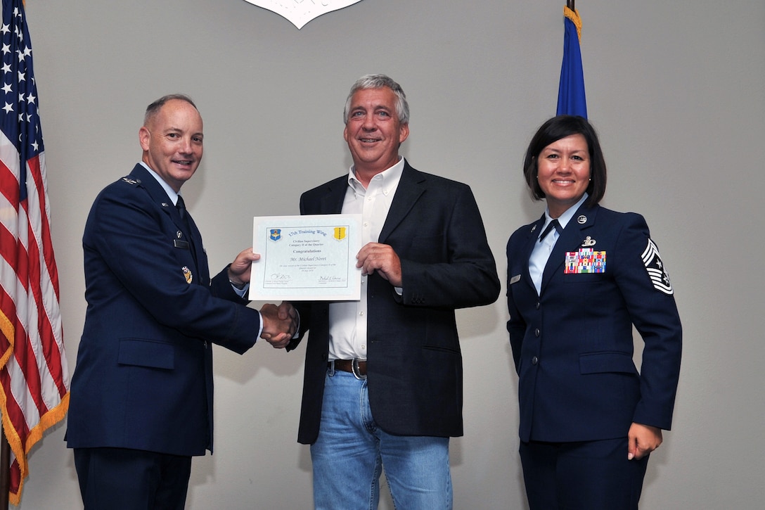 U.S. Air Force Col. Michael Downs, 17th Training Wing Commander, and Chief Master Sgt. JoAnne Bass, 17th Training Wing Command Chief, present the 17th Training Wing Civilian Category II Supervisory of the Quarter award to Michael Noret, 17th Civil Engineer Squadron, during the wing quarterly awards ceremony at the Event Center on Goodfellow Air Force Base, Texas, July 29, 2016. (U.S. Air Force photo by Staff Sgt. Laura R. McFarlane/Released)