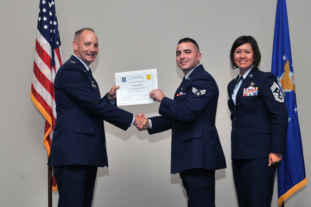 U.S. Air Force Col. Michael Downs, 17th Training Wing Commander, and Chief Master Sgt. JoAnne Bass, 17th Training Wing Command Chief, present the 17th Training Wing Volunteer of the Quarter award to Senior Airman Stephen Muldoon, 17th Medical Support Squadron, during the wing quarterly awards ceremony at the Event Center on Goodfellow Air Force Base, Texas, July 29, 2016. (U.S. Air Force photo by Staff Sgt. Laura R. McFarlane/Released)