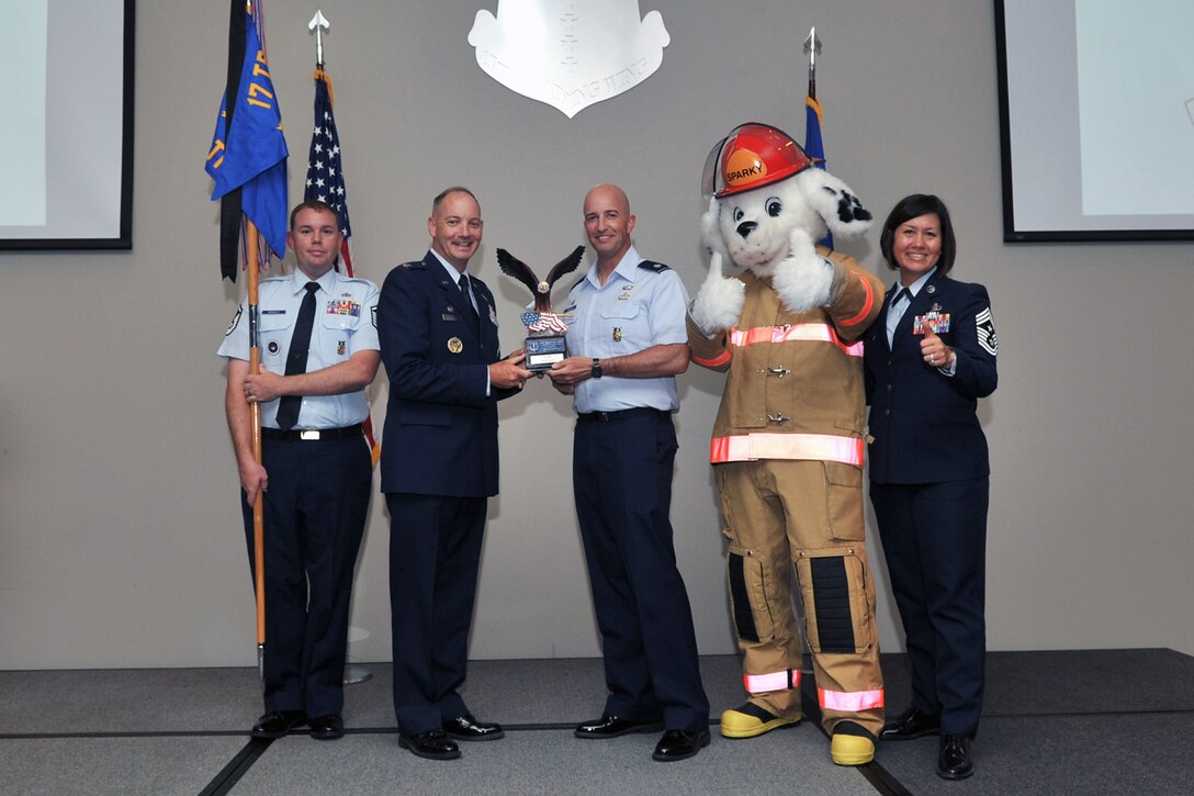 U.S. Air Force Col. Michael Downs, 17th Training Wing Commander, and Chief Master Sgt. JoAnne Bass, 17th Training Wing Command Chief, present the 17th Training Wing Unit of the Quarter award to Lt. Col. Matthew Welling, 312th Training Squadron Commander, during the wing quarterly awards ceremony at the Event Center on Goodfellow Air Force Base, Texas, July 29, 2016. (U.S. Air Force photo by Staff Sgt. Laura R. McFarlane/Released)