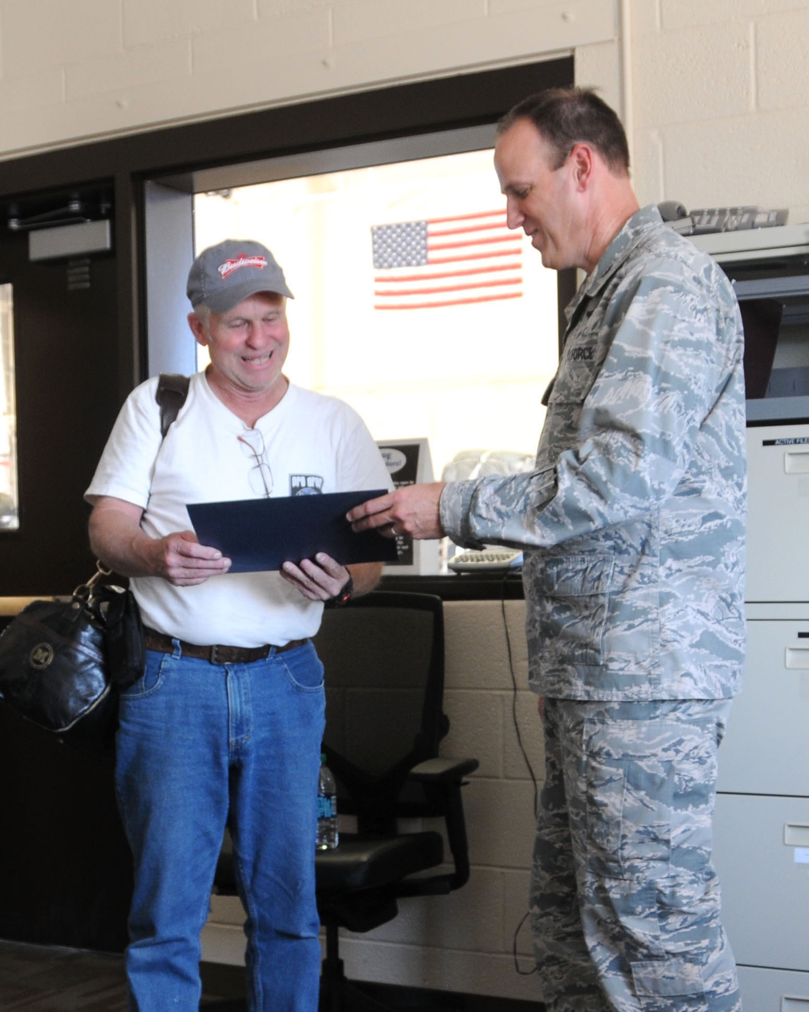 120th Airlift Wing Commander Col. Lee Smith presents a certificate of appreciation to Robert Marquard recognizing him as the unit's first space-a travel passenger.  Marquard is a retiree who served 40 years with the Montana Air National Guard. (U.S. Air National Guard photo/Tech. Sgt. Michael Touchette)